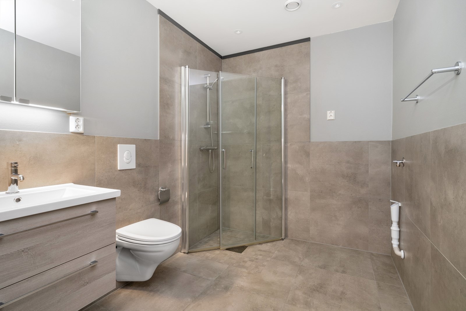 Delikat baderom med flislagt gulv med vannbåren gulvvarme, vegger har flis og tapet på vegg og i himling er malt med spotter Galleribilde