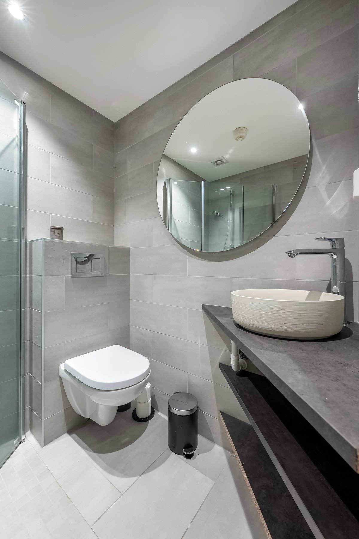 Flislagt bad fra 2019 med veggmontert toalett og åpen servantløsning. Galleribilde