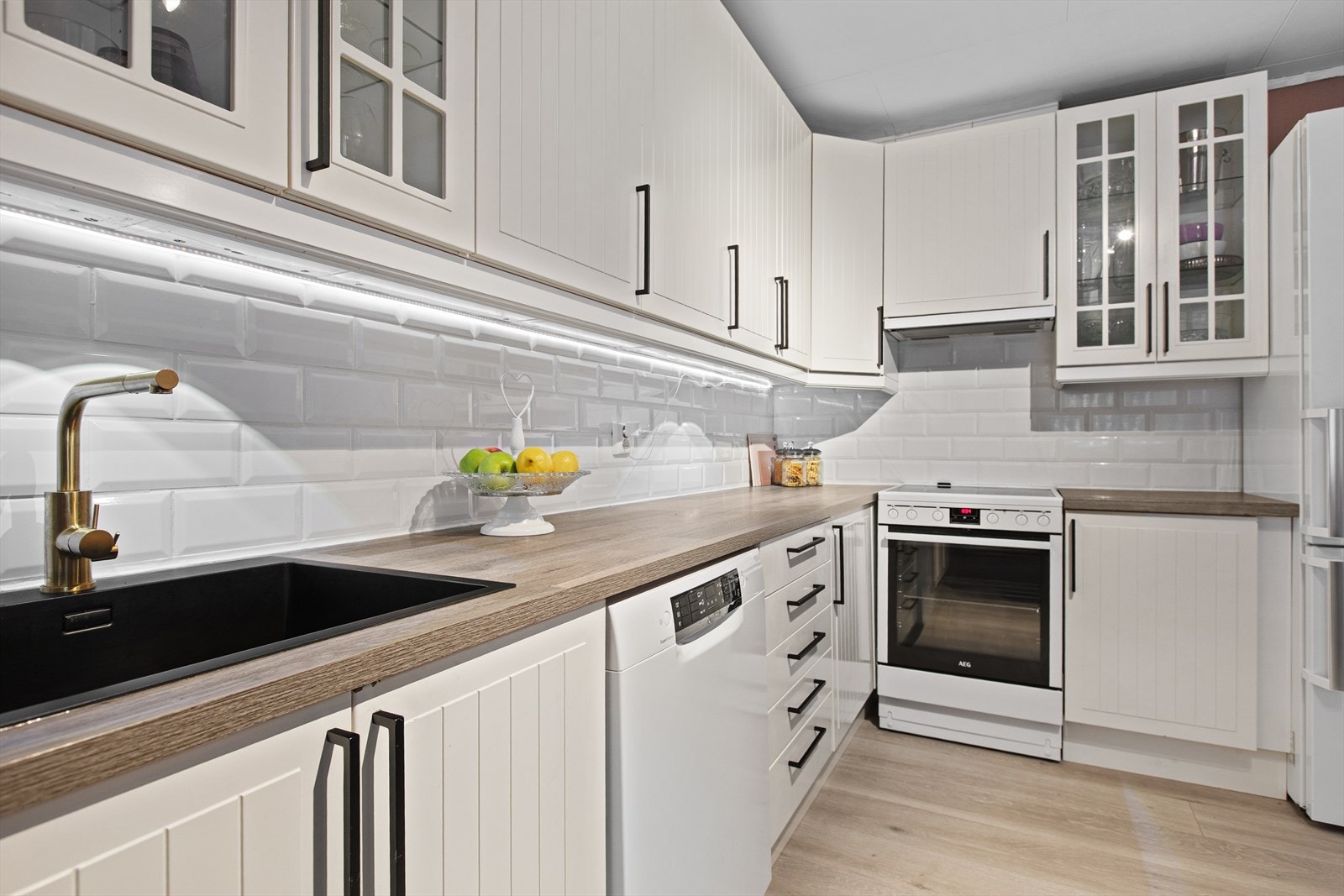 Mørk benkeplate i laminat og hvite fliser mellom benk og overskap. Galleribilde