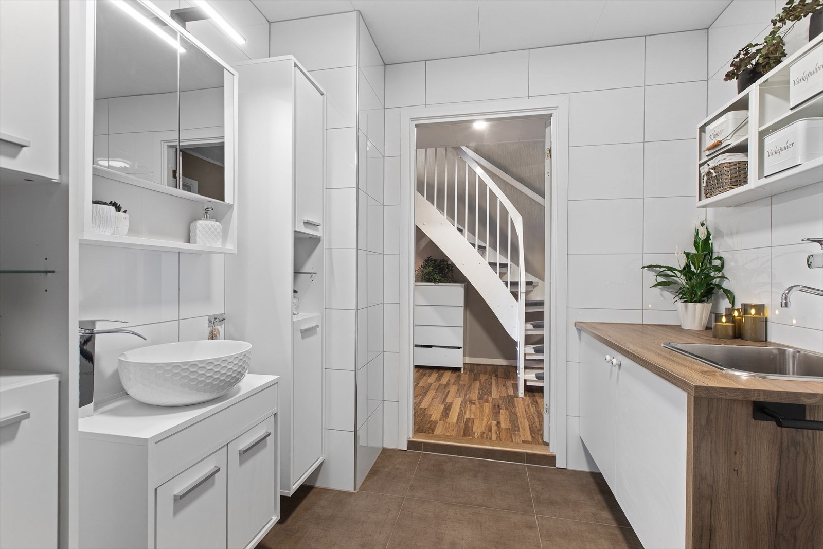 Her er det varme i de brune gulvflisene og en praktisk benk med utslagsvask. Galleribilde