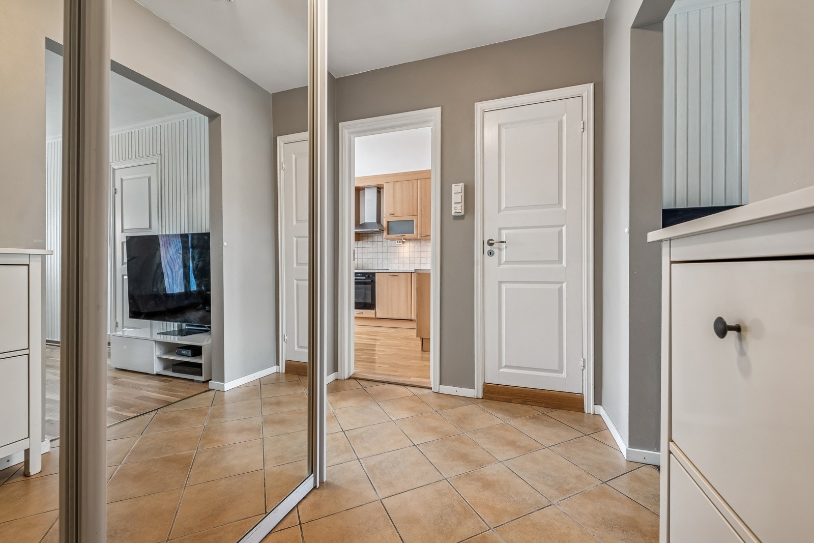 Entreén er et knytepunkt i leiligheten. Med takhøye skyvegarderober med speil i front og skoskap er det lett å holde orden. Galleribilde