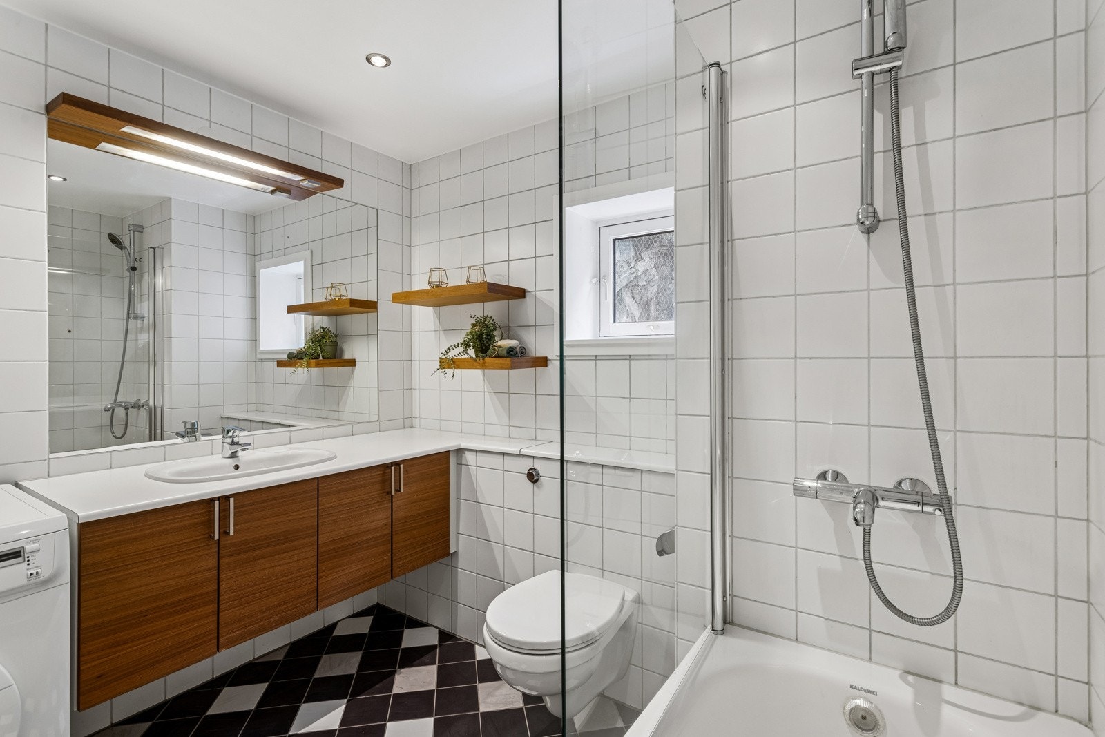 Innbydende baderom med servant nedfelt i laminat benkeplate, underskap og innfliset speil med overlys. Galleribilde