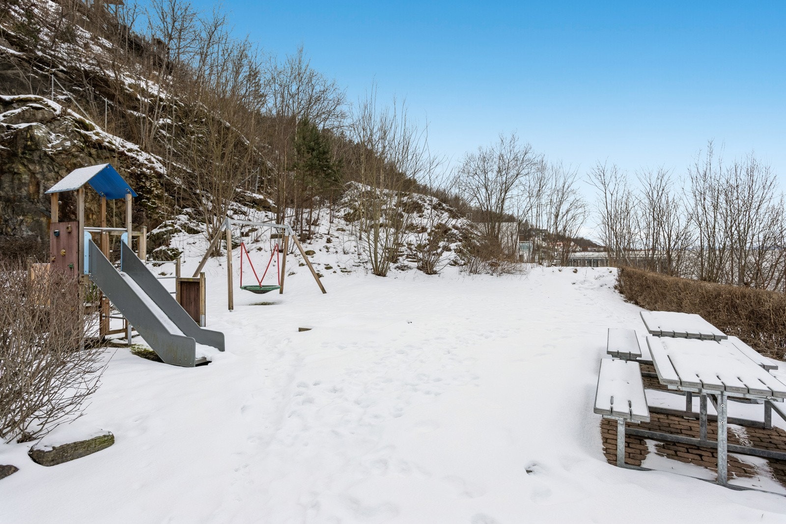 Tomten er opparbeidet med asfalterte adkomstveier, gressplen, beplantning, lekeplasser og sittegrupper. Galleribilde