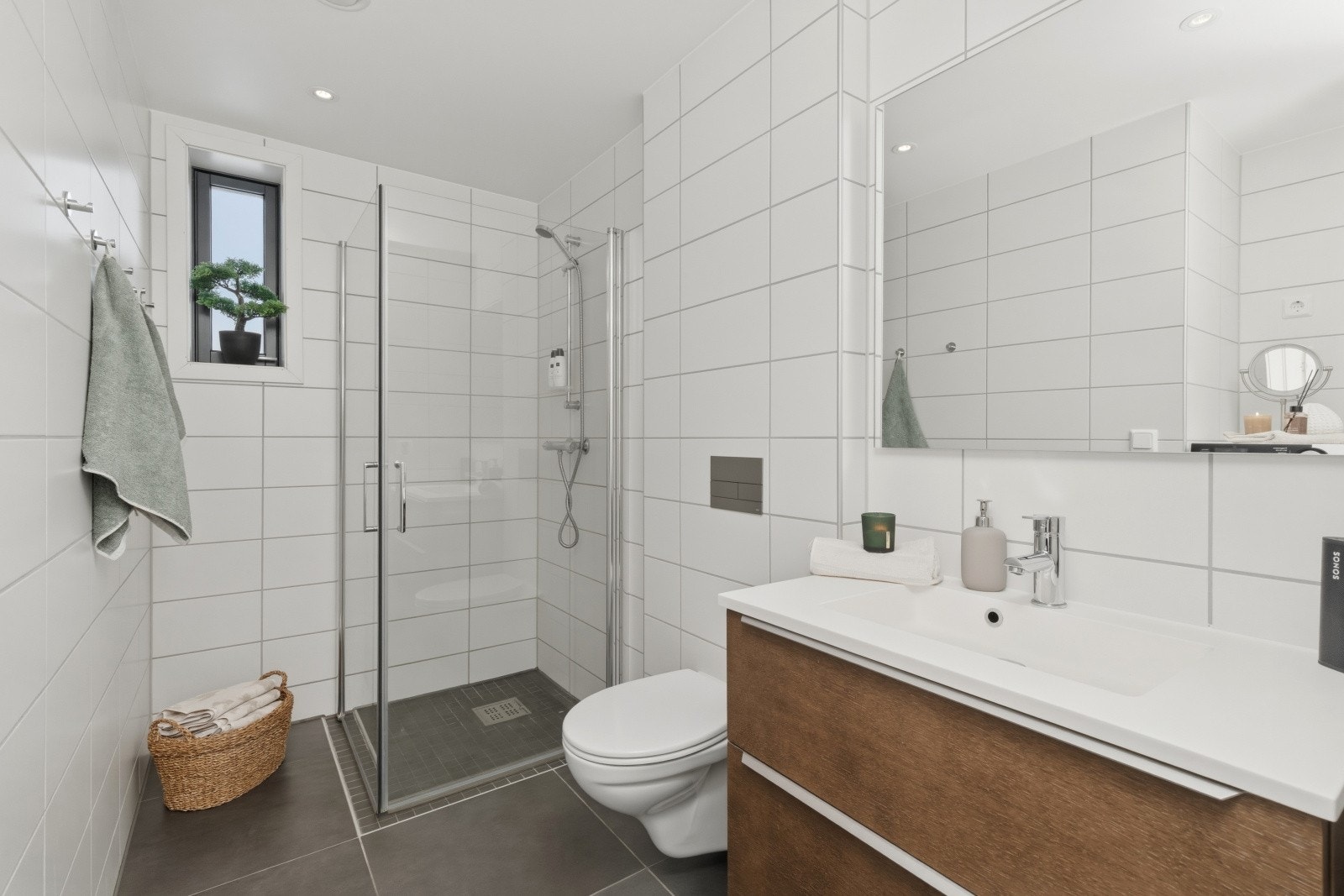 Badet er delikat innredet med store, grå fliser på gulvet og hvite fliser på vegg. I gulvet har man også varmekabler for ekstra komfort. Galleribilde