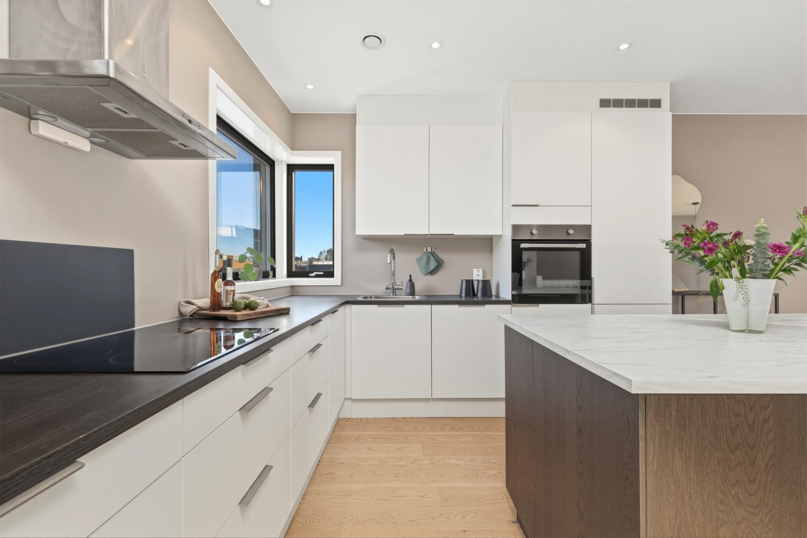 Kjøkkenet er stilrent innredet med en kombinasjon av hvite og trefargede, slette fronter og benkeplate i laminat. Galleribilde