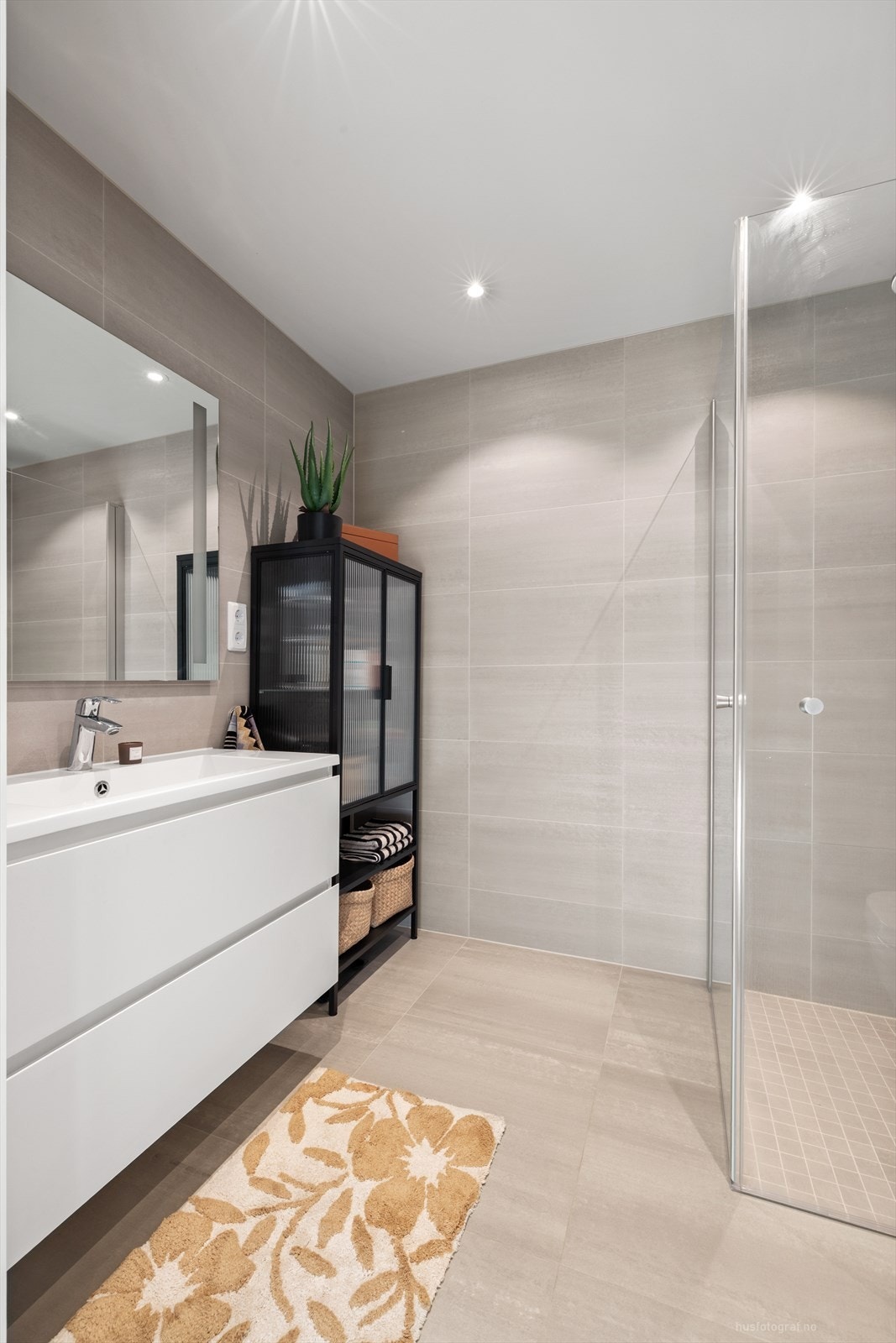 Hvit baderomsinnredning med heldekkende nedfelt servant, rom for oppbevaring i skuffeseksjon og speil med LED-belysning. Galleribilde