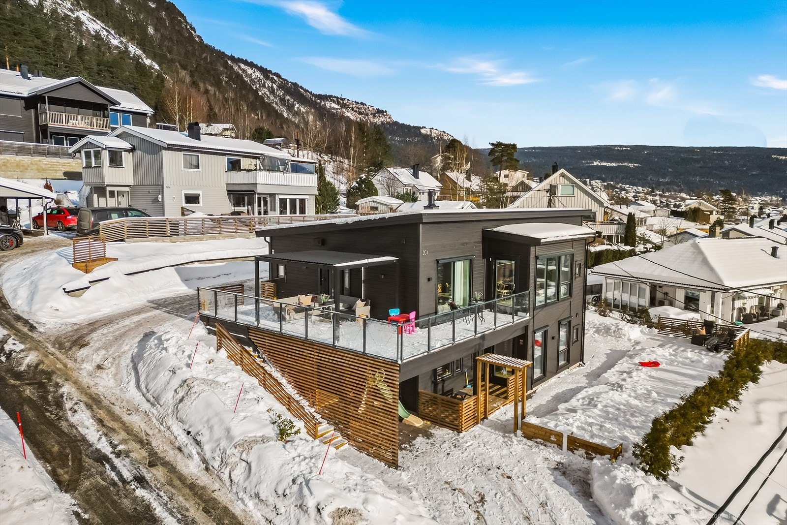 Tomten er skrående, og boligen er plassert i terrenget slik at man har en enkel utvendig adkomst til begge etasjene. Galleribilde