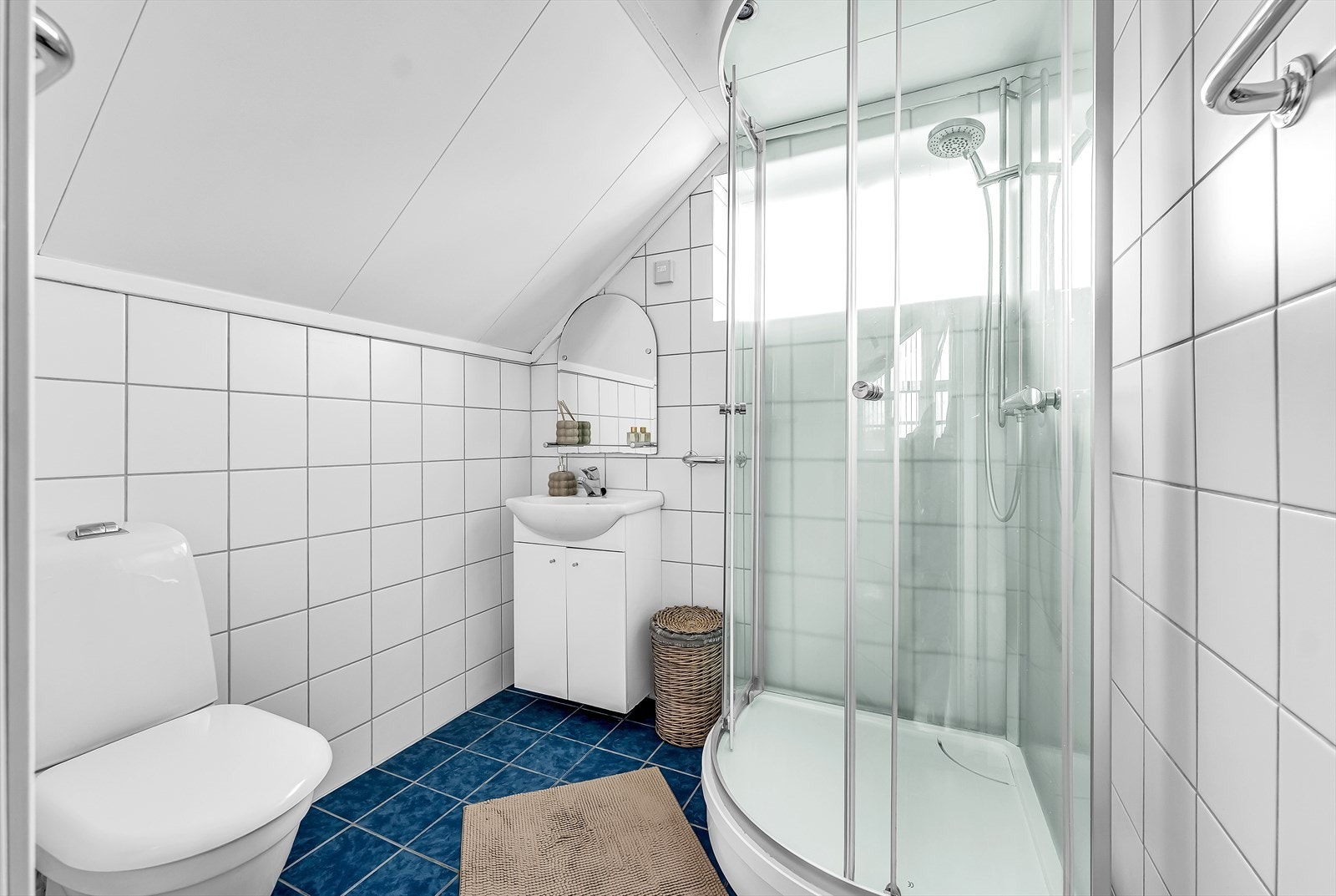 Baderommet er innredet med dusjkabinett, gulvmontert toalett og servant med skapinnredning. Galleribilde