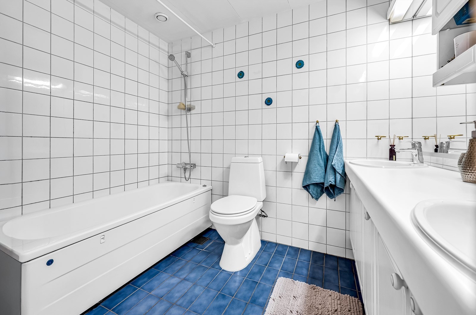 Rommet er utstyrt med badekar, gulvmontert toalett og dobbel servant med ettgreps blandebatterier, integrert i original baderomsinnredning. Galleribilde