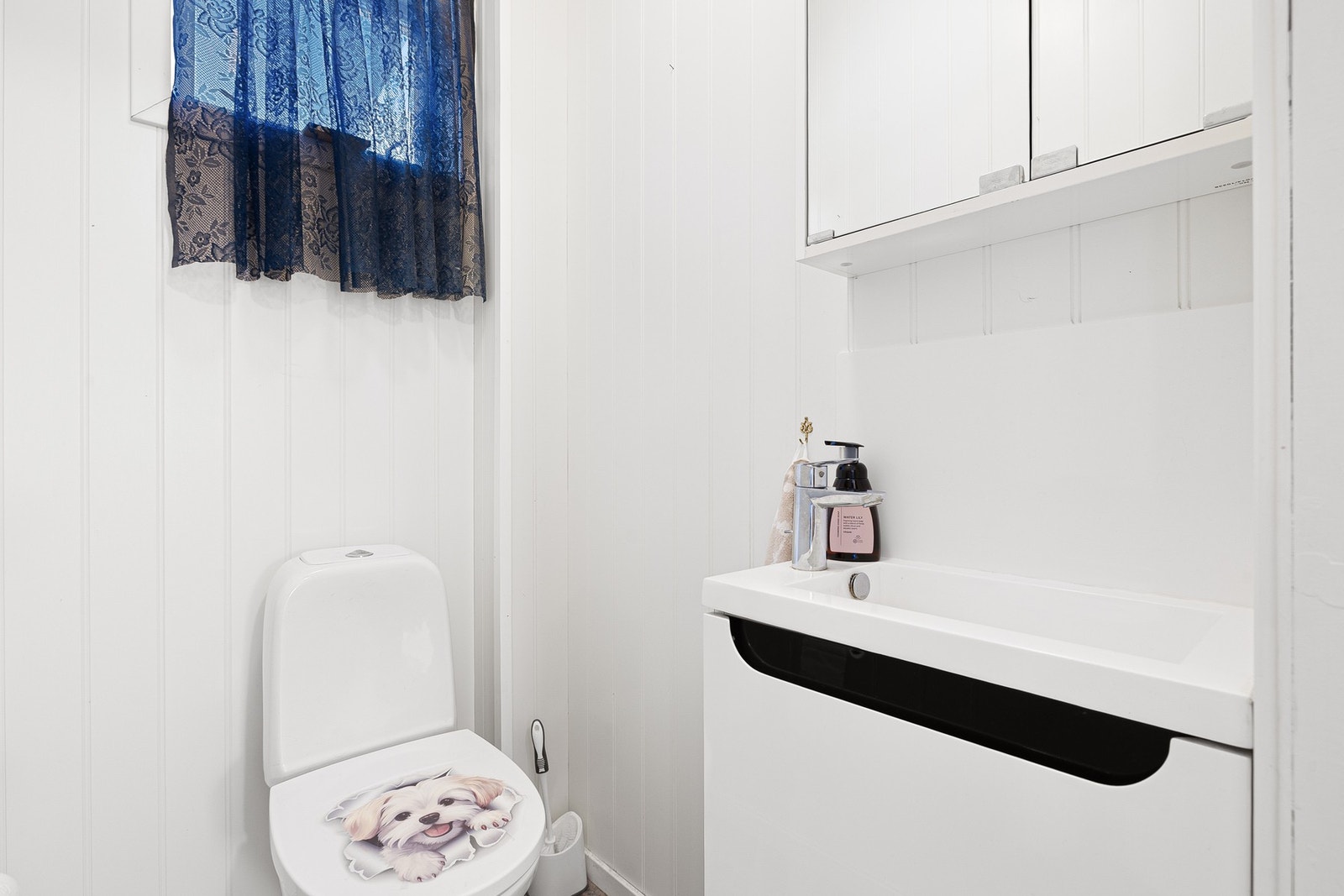 Toalettrom utstyrt med gulvmontert toalett, servantskap og servant. Galleribilde