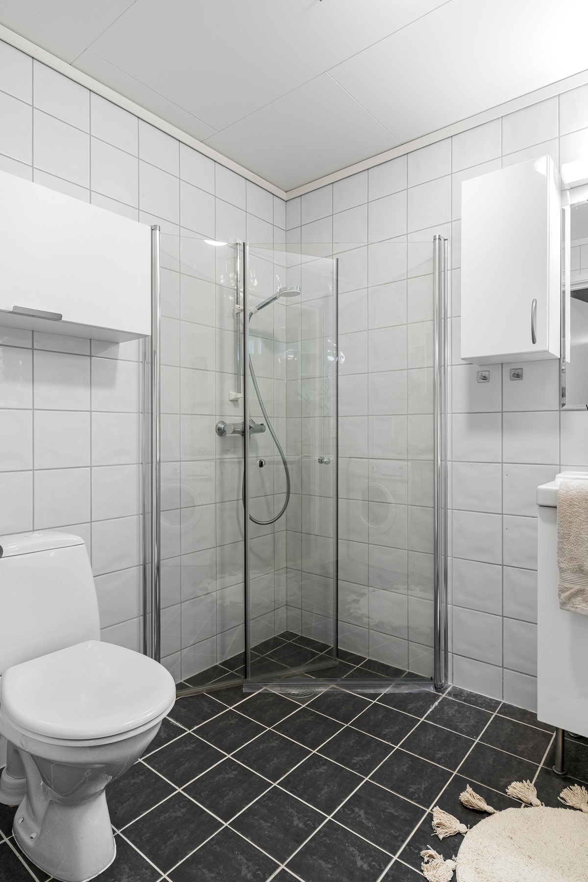 Badet er innredet med servantskap, veggskap og speilskap. Videre er rommet utstyrt med dusj, toalett og opplegg til vaskemaskin. Galleribilde