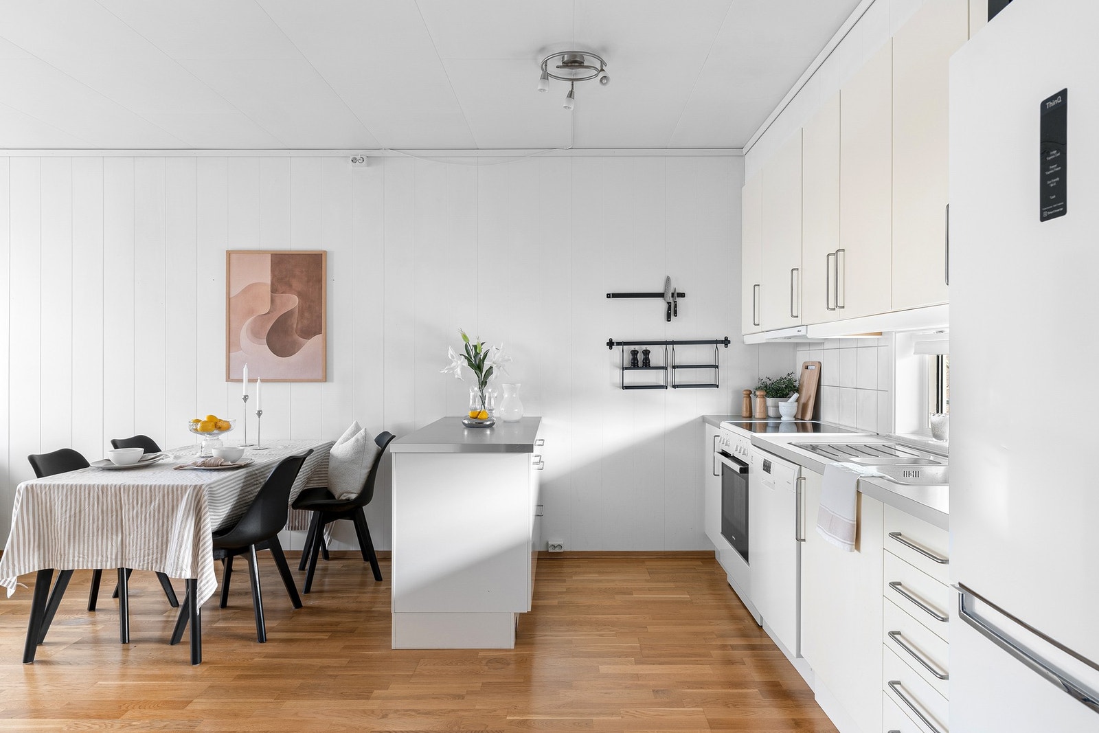 Kjøkkeninnredning med hvite slette fronter og benkeplate i laminat. Galleribilde