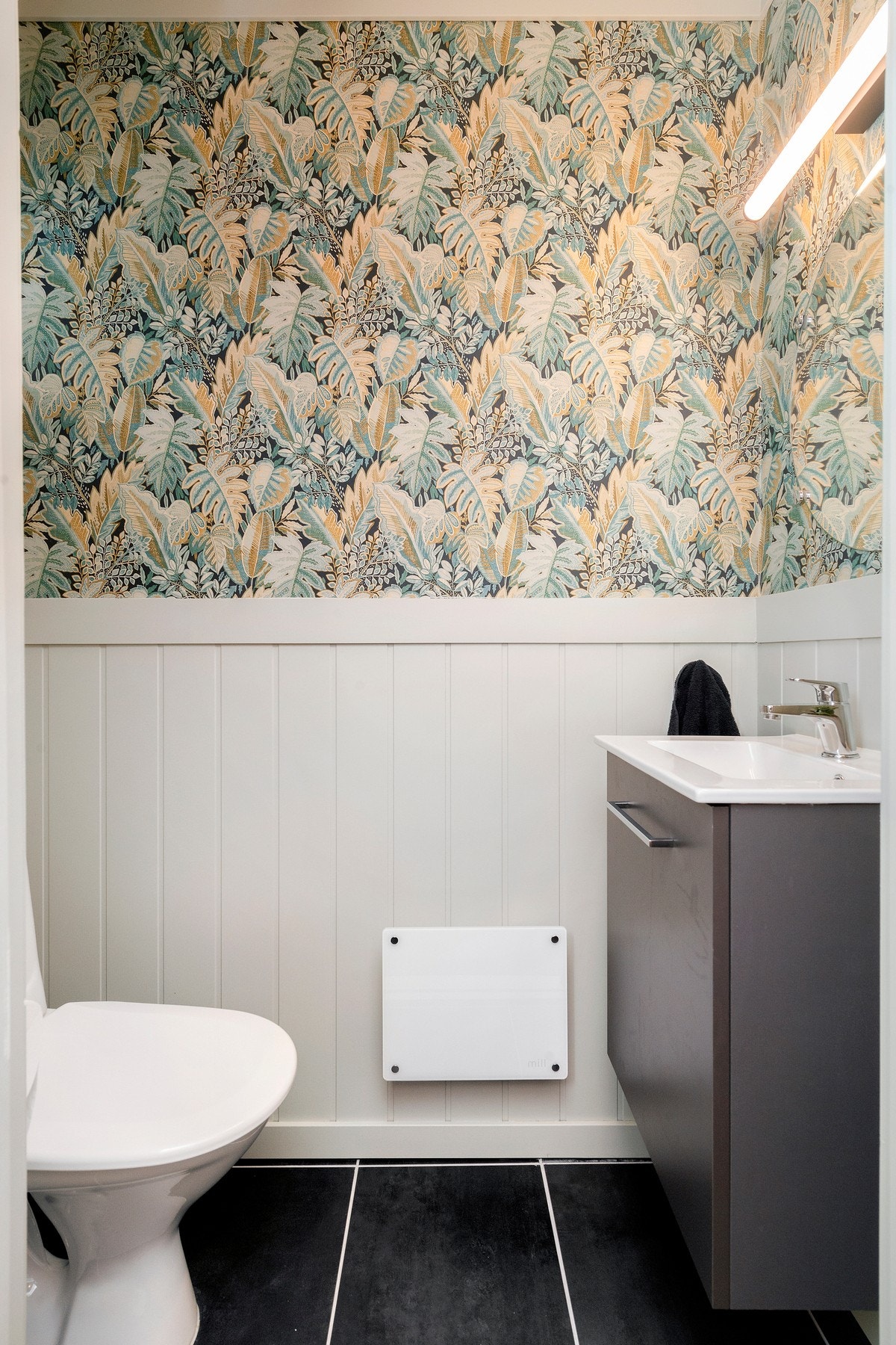 Stilrent toalett med gulvmontert toalett samt servantskap og speil Galleribilde