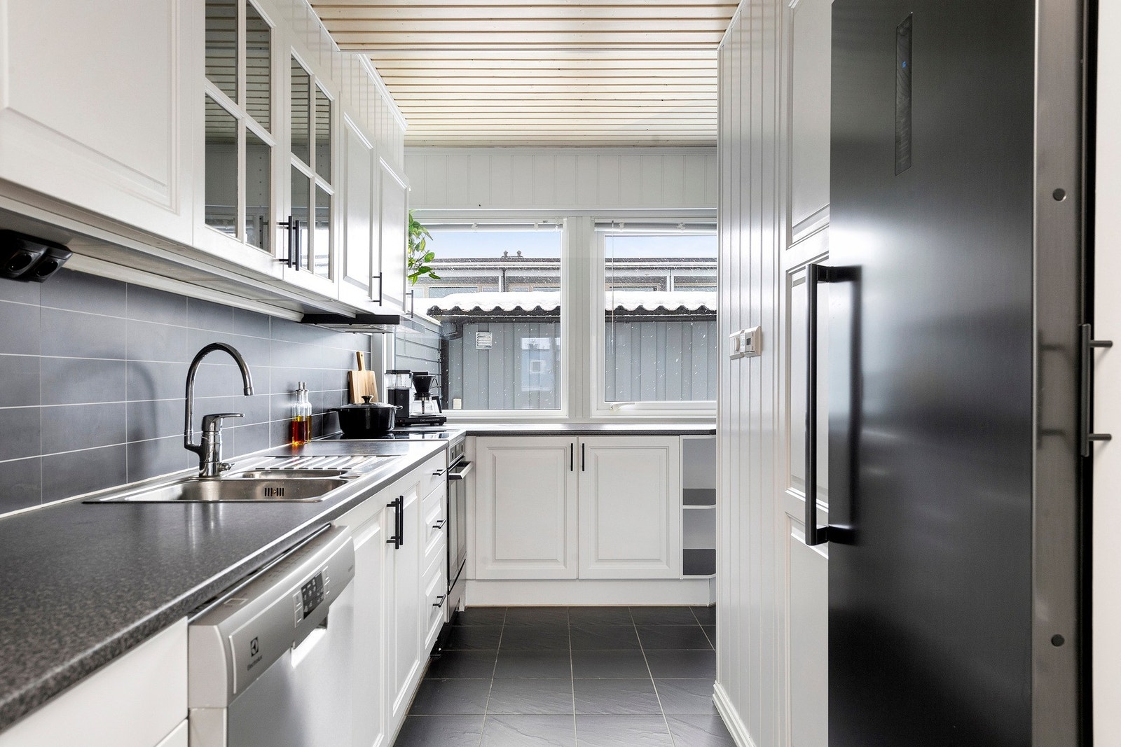 Delikat kjøkkeninnredning med hvite, profilerte fronter og laminat benkeplate Galleribilde