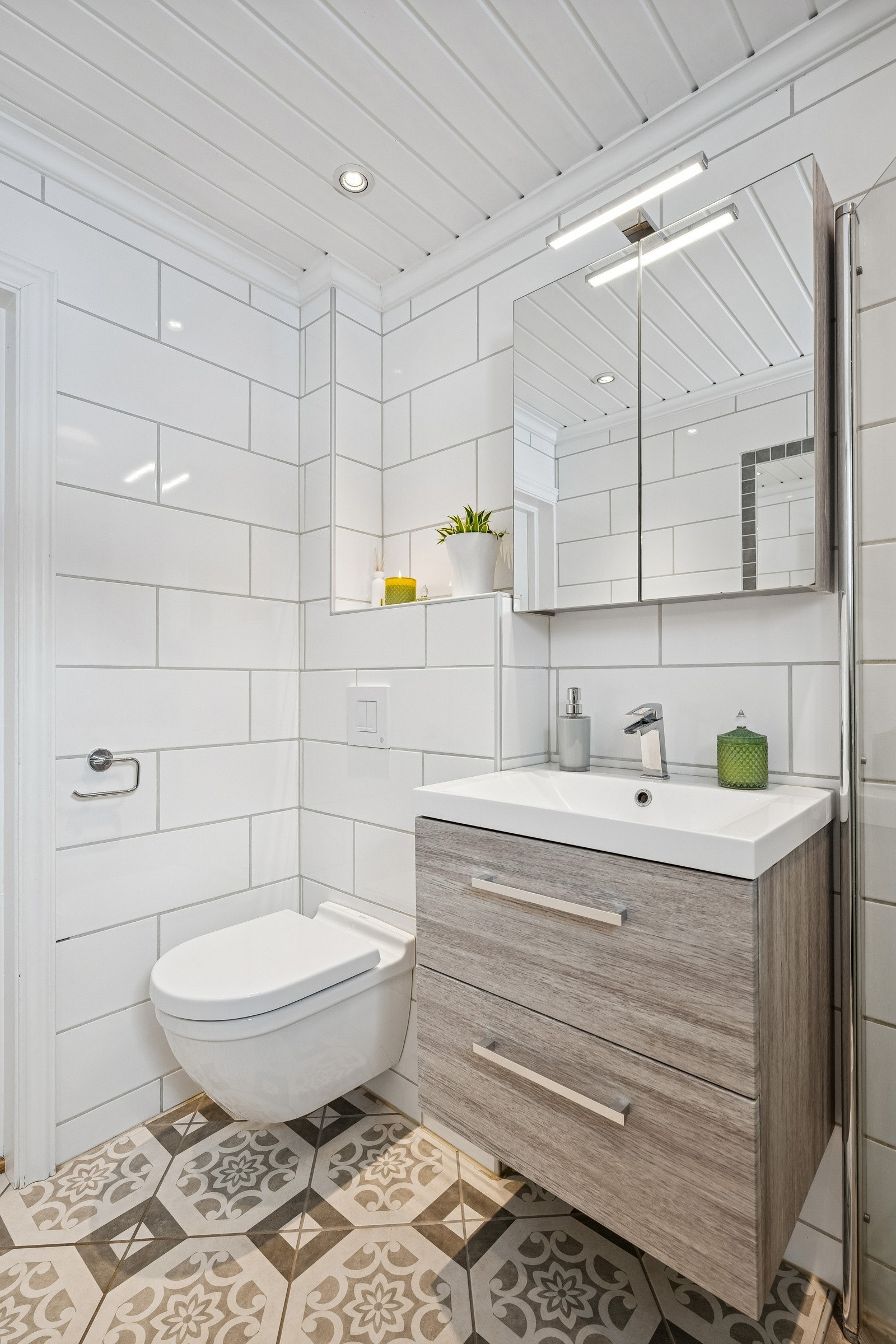 Utstyrt med vegghengt toalett, dusjhjørne og servantskap med heldekkende servanttopp og speilskap på vegg. Galleribilde