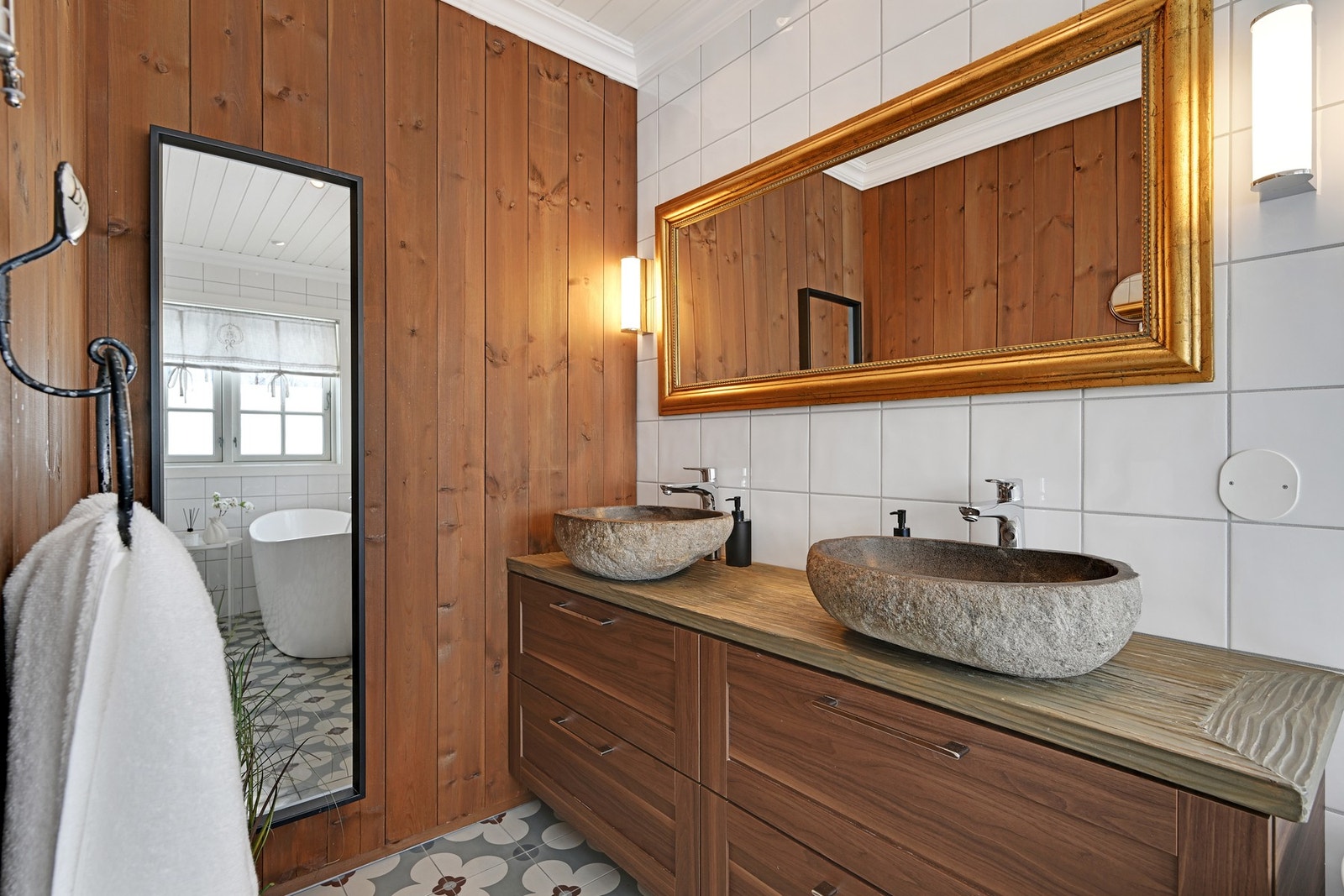 Badet er pent innredet og det er en fin kombinasjon av tre og fliser på veggene Galleribilde