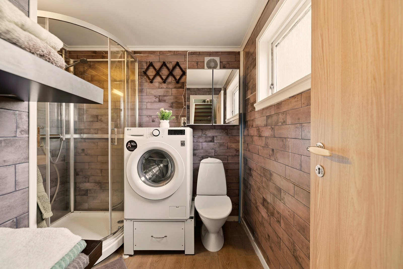 Baderommet inneholder baderomsmøbel med profilerte fronter, heldekkende servant og ett-greps blandebatteri, speil, vegglampe, gulvstående toalett, opplegg for vaskemaskin,
speilskap og dusjkabinett. Galleribilde