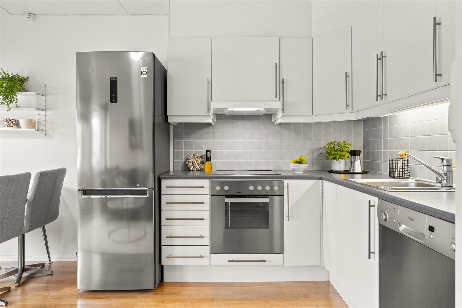 Kjøkkenet har en lys innredning med glatte fronter, laminert benkeplate og flislagt vegg mellom over- og underskap. Komfyr og oppvaskmaskin medfølger. Galleribilde