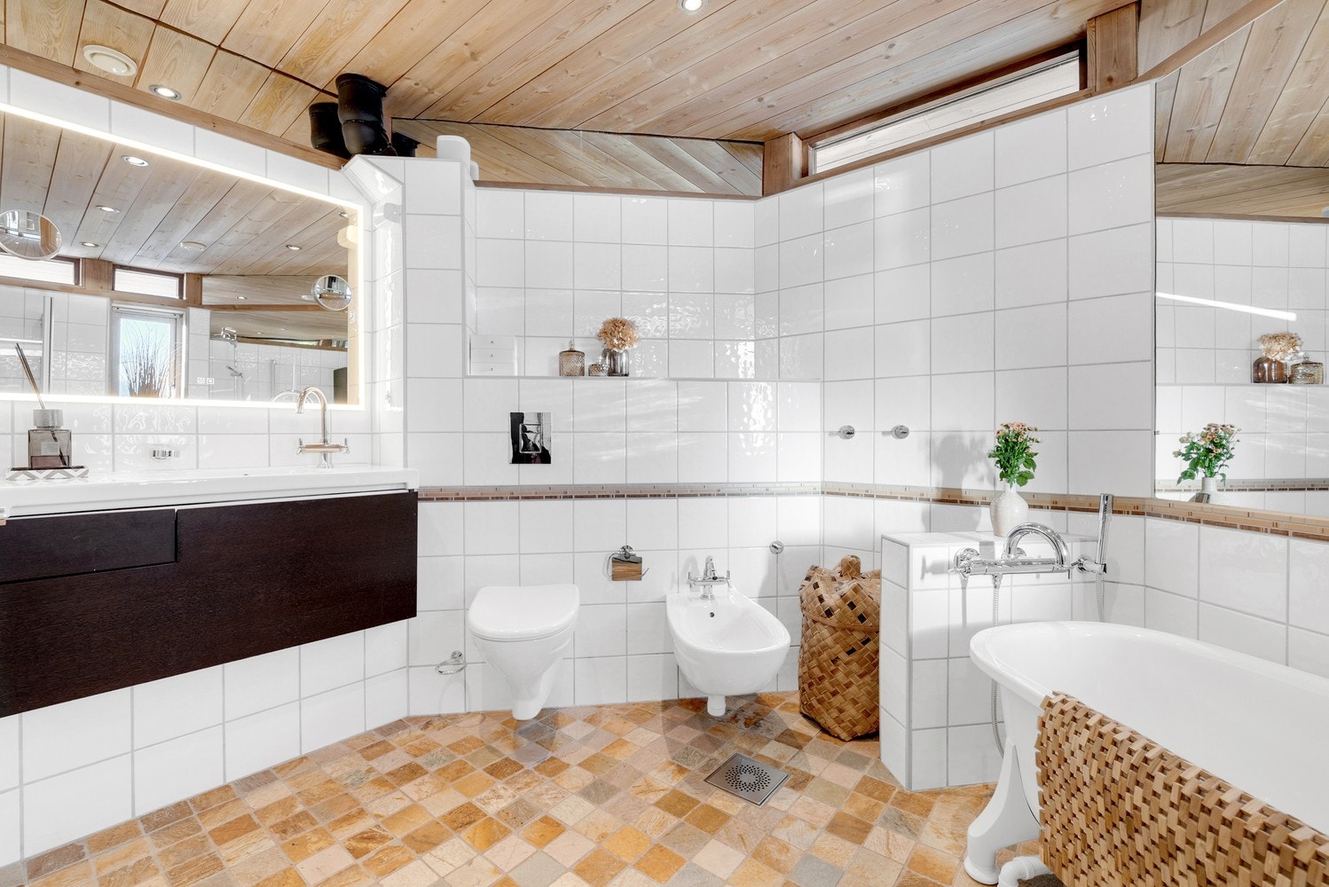 Stilrent baderom med praktisk planløsning, vegghengte sanitærløsninger og moderne servantinnredning med god belysning. Galleribilde