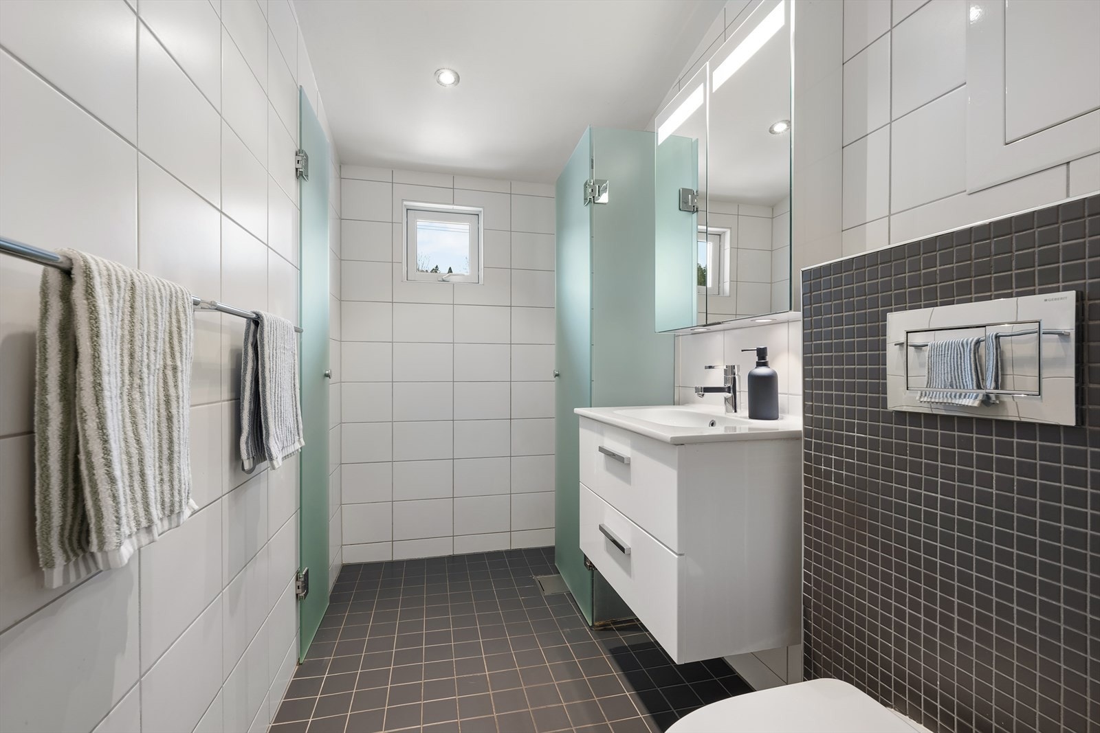 Pent bad fra 2010 med flislagte overflater, varmekabler og spotter i taket. Galleribilde