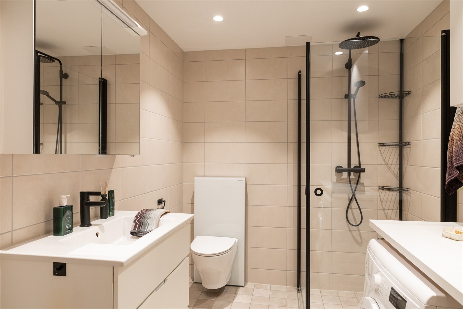 Badet er innredet med vegghengt klosett, servant nedfelt i innredning, speilskap og dusjhjørne med svingbare glassdører. Galleribilde