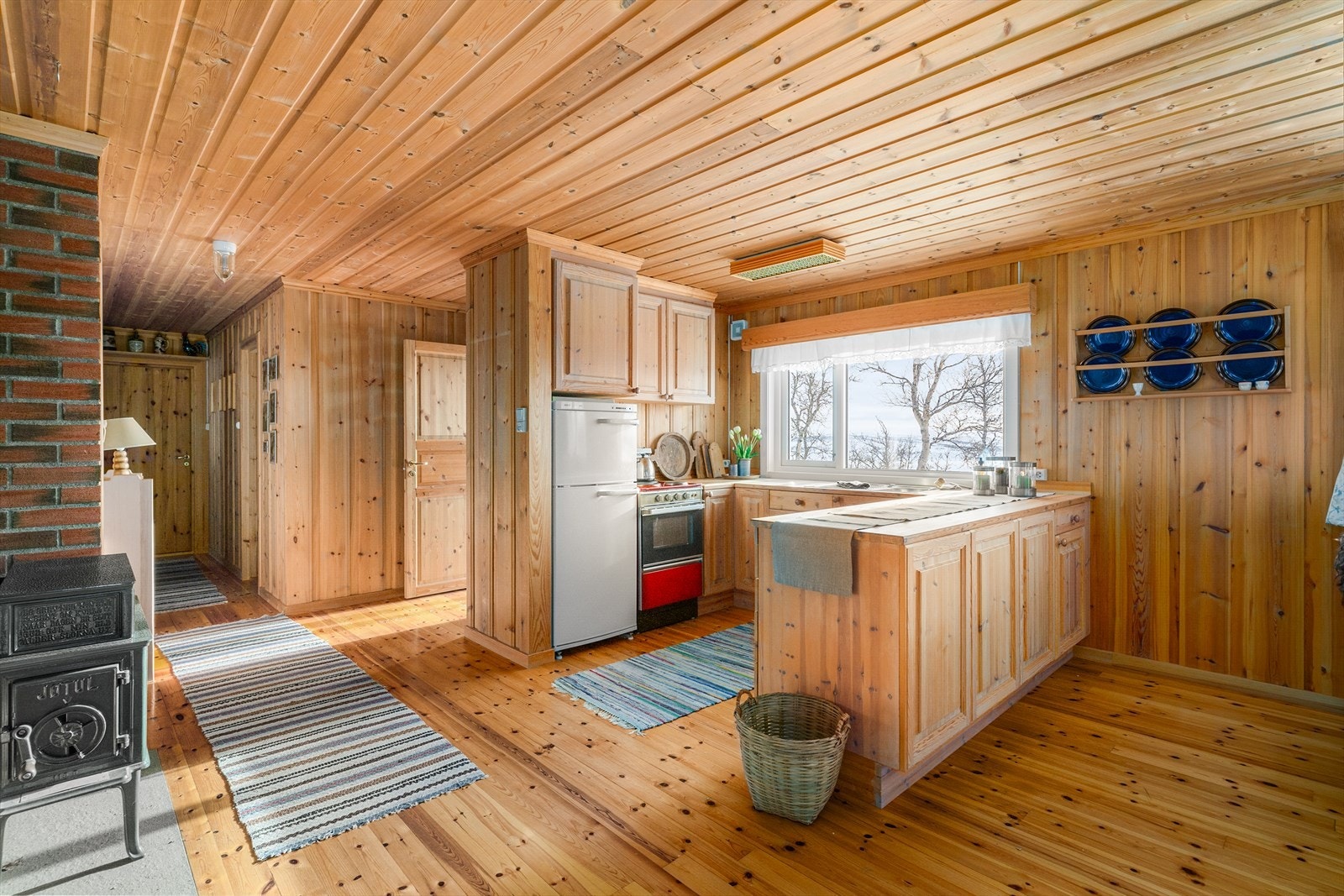 Fin kjøkkenkrok i åpen løsning, med takhøy kjøkkeninnredning og halvøy ut mot spisestuen. Det er godt med skapplass. Galleribilde