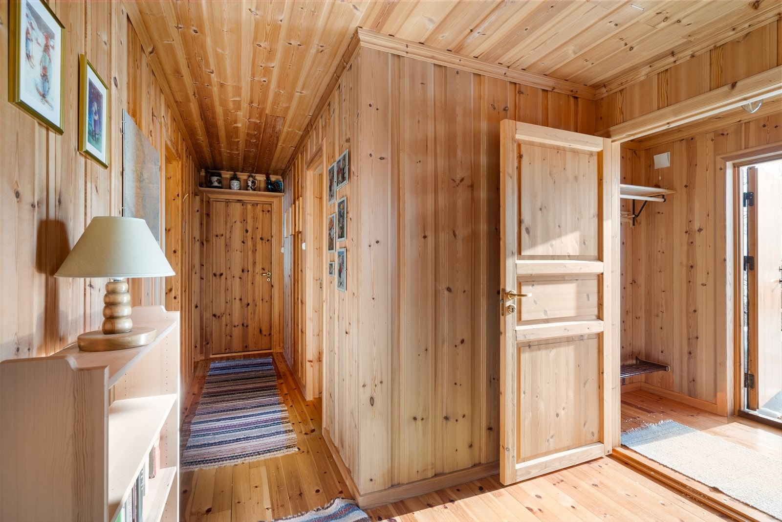 Gang i åpen løsning med stuen. Innvendige overflater består hovedsakelig av furugulv, samt trepanel på vegger og i tak. Galleribilde