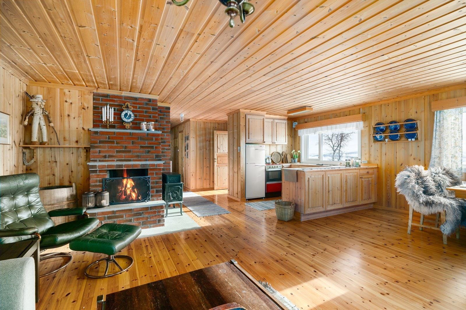 Sentralt i rommet er det etablert ildsted med både åpen peis og vedovn, som sørger for lun og god varme. Galleribilde