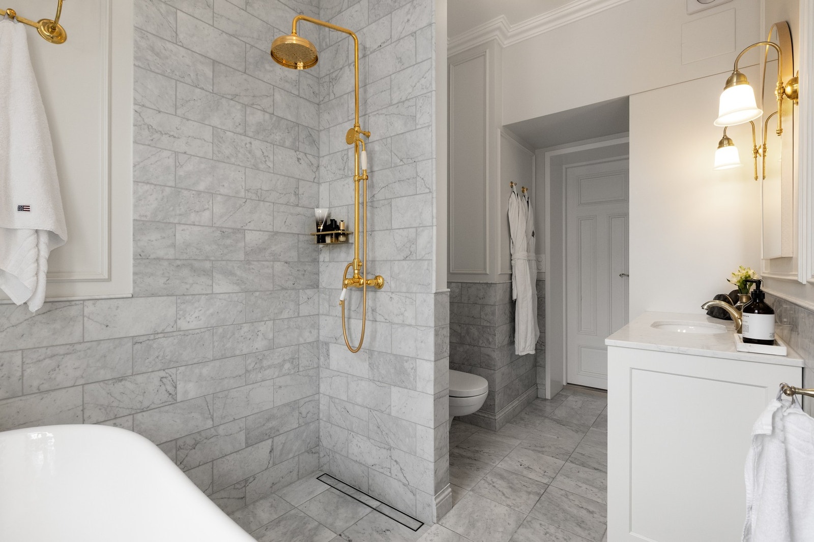 Rommet har flislagte gulv og veggflater i ekte marmor, kombinert med enkelte malte plater, samt hvitmalt, slett himling som gir et lyst og helhetlig uttrykk. Det er installert varmekabler i gulvet for god komfort, samt taklampe og belysning ved speil som Galleribilde