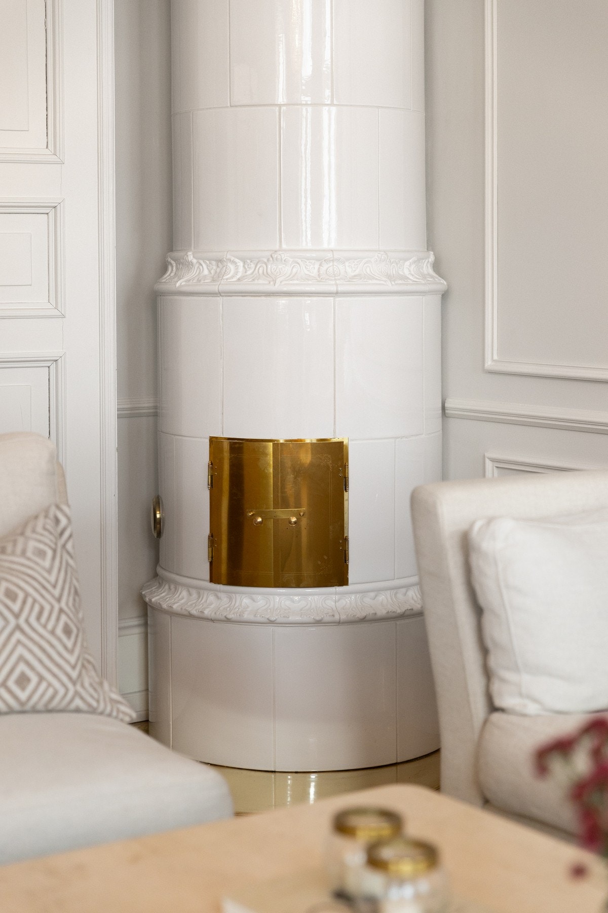 Den hvite kakkelovnen (2025) med ornamenter og messingluke skaper både stemning og ekstra komfort. Galleribilde