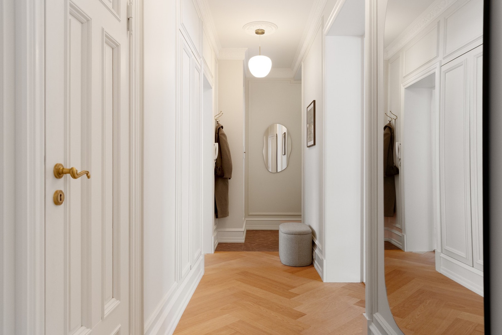 Entréen er lys og innbydende med gjennomført klassisk stil. Her møtes du av vakker stukkatur, profilerte vegglister og speilfelt som harmonerer med boligens øvrige uttrykk. Galleribilde