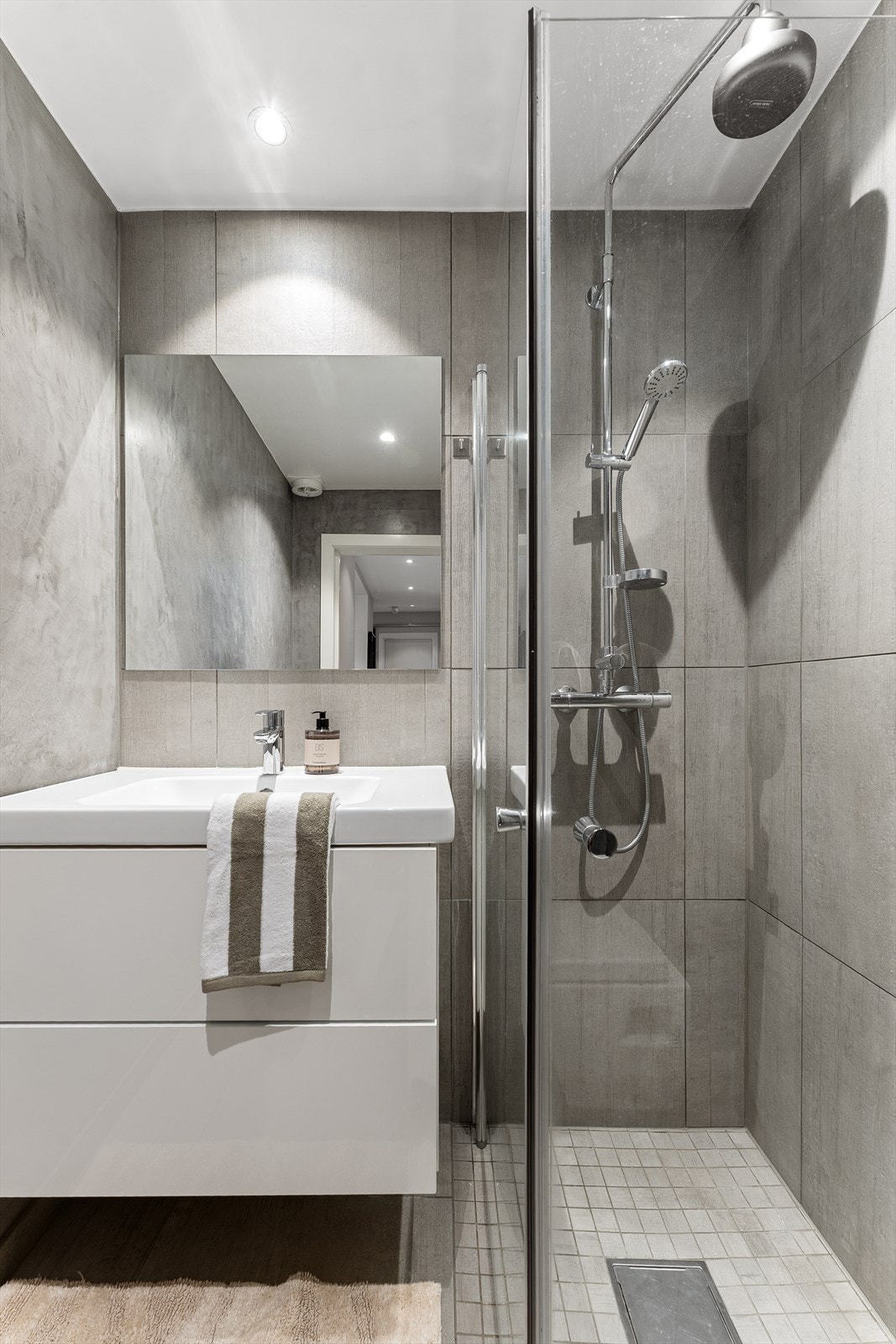 Baderomsinnredningen består av lyst benkeskap med glatte fronter, samt speil plassert over servanten. Galleribilde