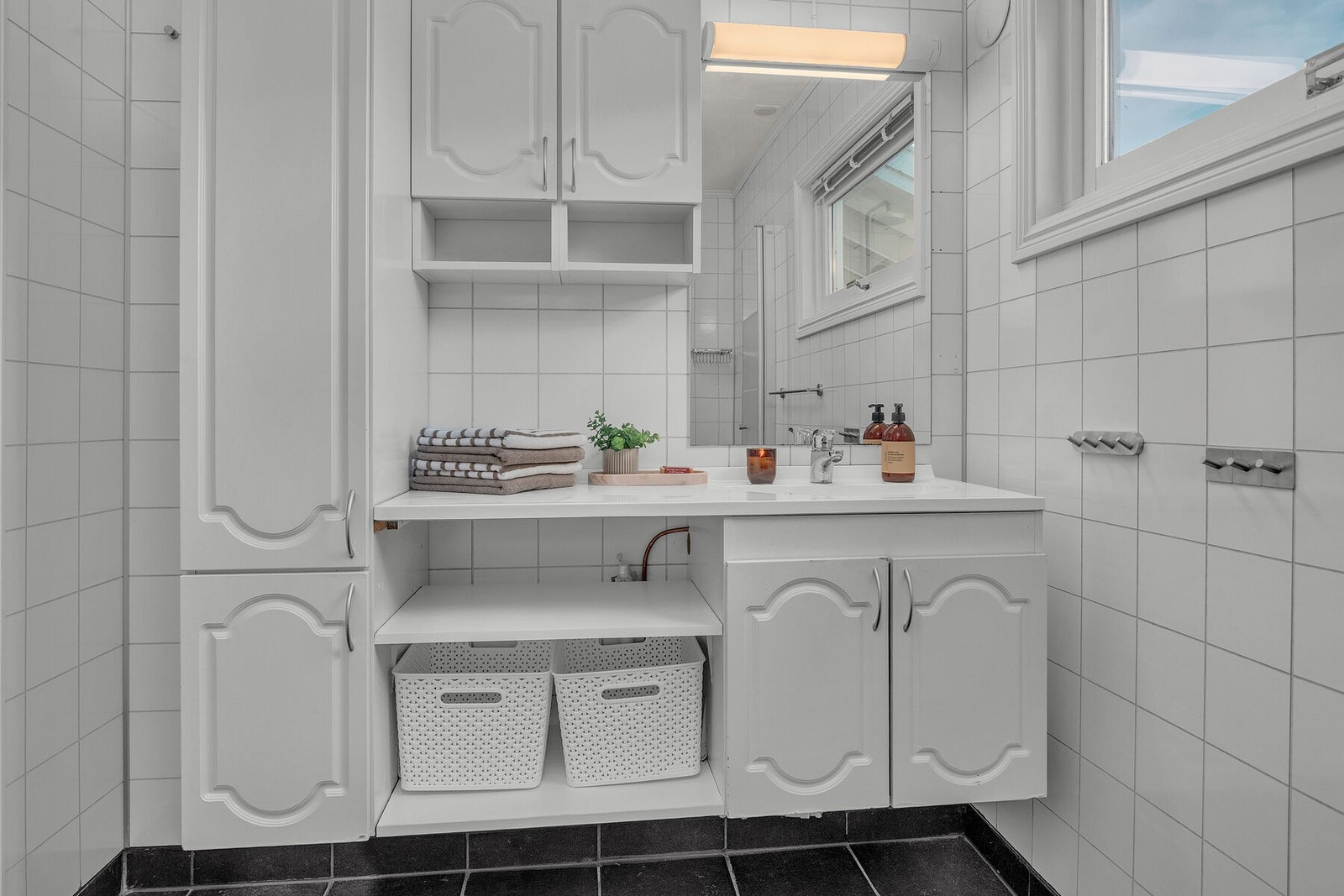 Praktisk bad med baderomsplater på vegger og flislagt gulv med behagelig elektrisk gulvvarme. Galleribilde