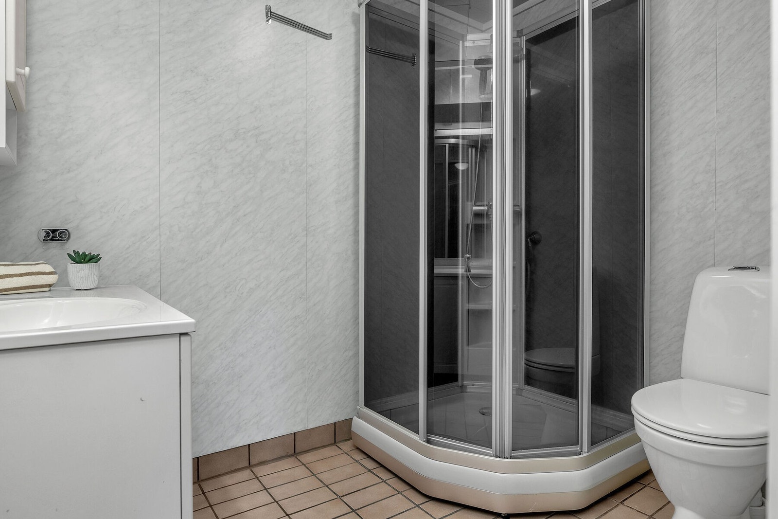 Badet er innredet med toalett, dusjkabinett og servant på innredning. Galleribilde