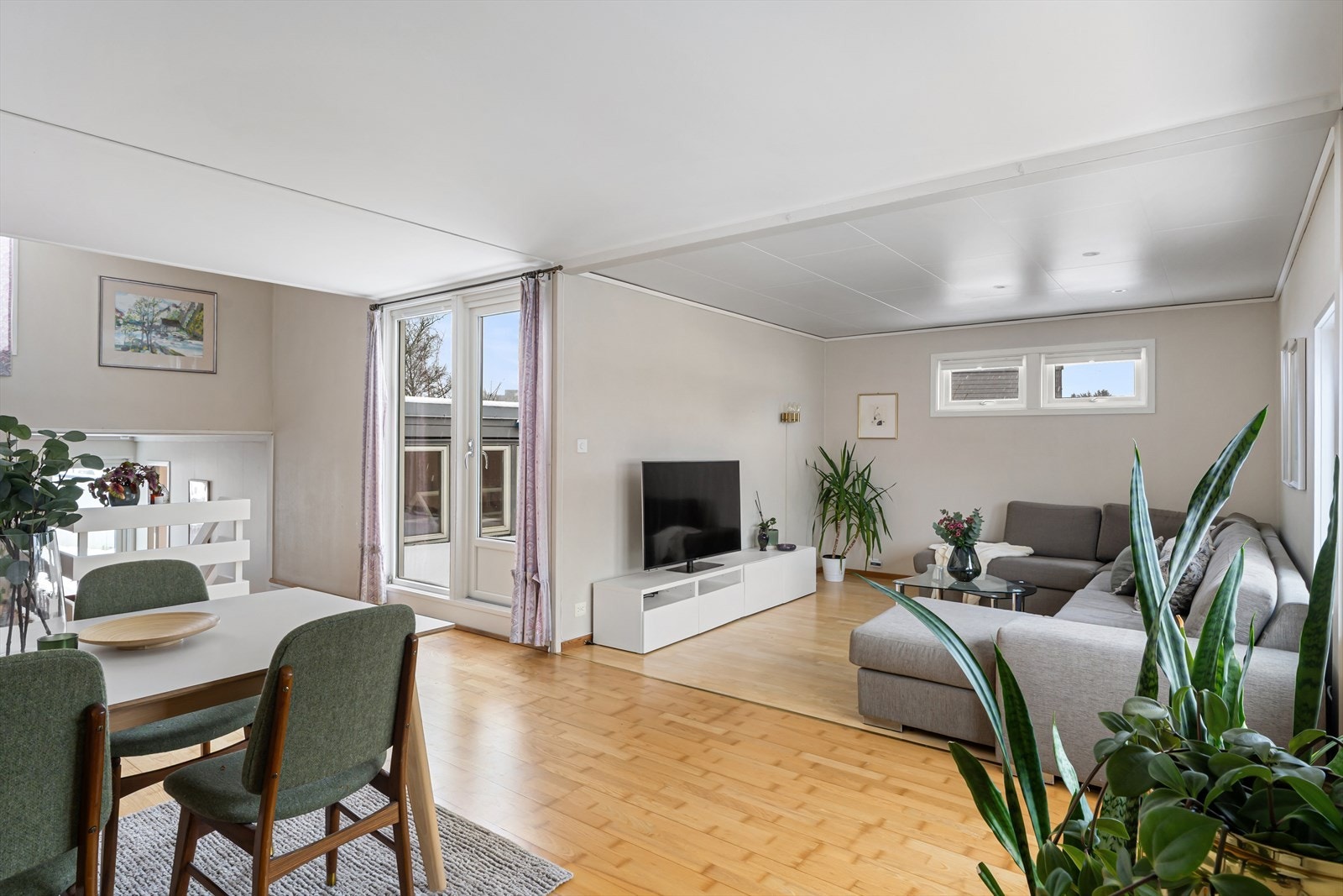 Lys og romslig stue i vinkel med parkett på gulv og lysmalte flater Galleribilde