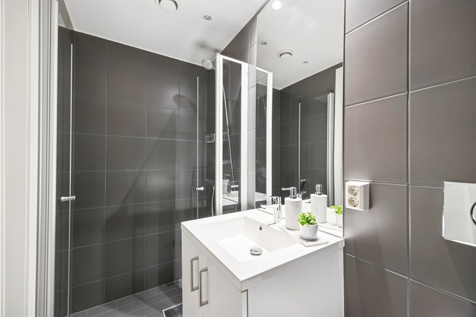 Stilren innredning består av vegghengt wc, servant m/underskap, speil og dusj med innfellbare glassdører. Galleribilde