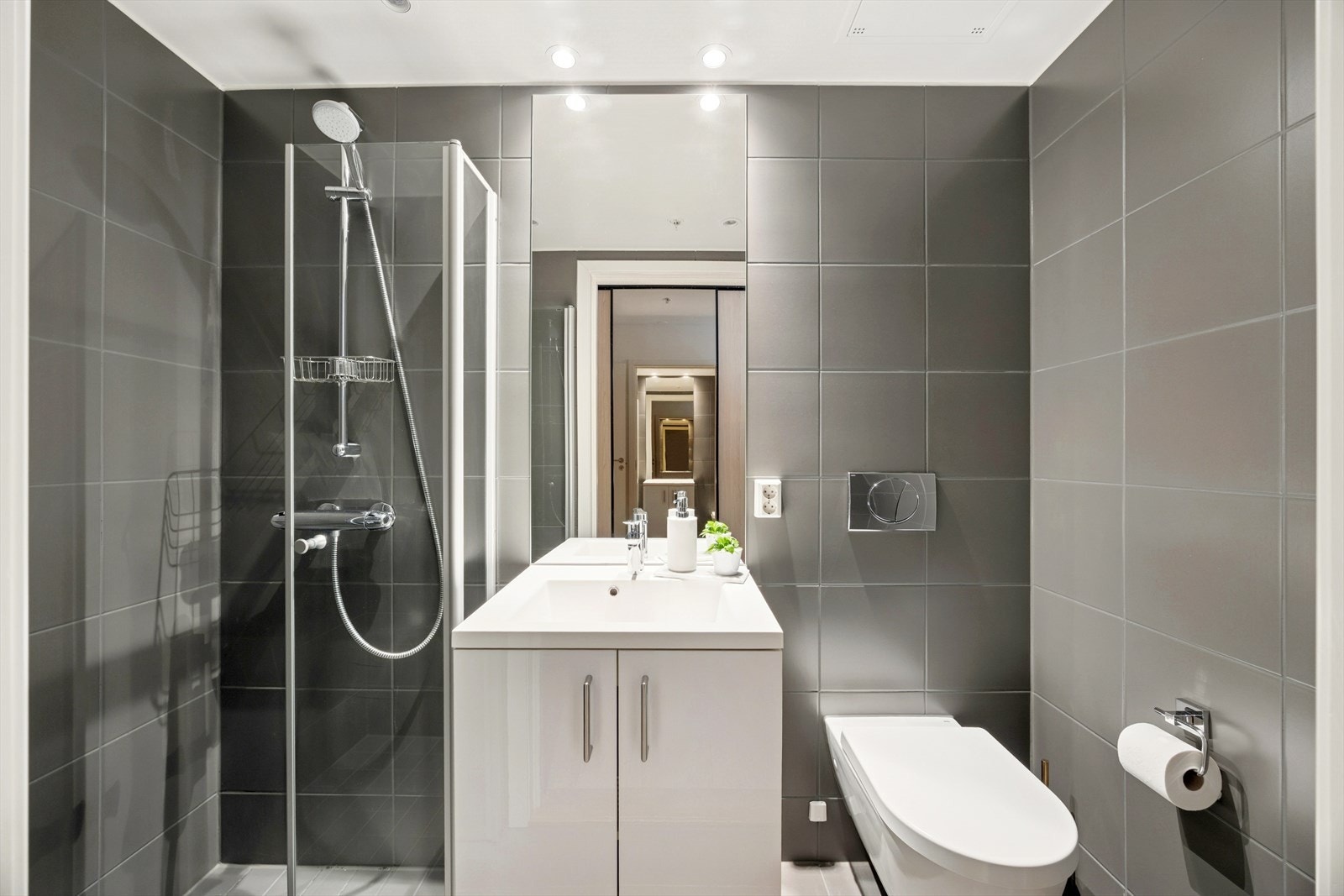 Baderom nummer to (potensielt del hybel) har mørke pene fliser på gulv og vegg. Galleribilde