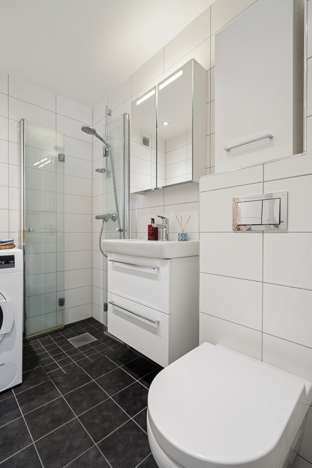 Badet ble renovert i 2015 og fremstår lyst og moderne, med fliser, innfellbare dusjvegger i glass, vegghengt toalett og praktisk innredning. Galleribilde