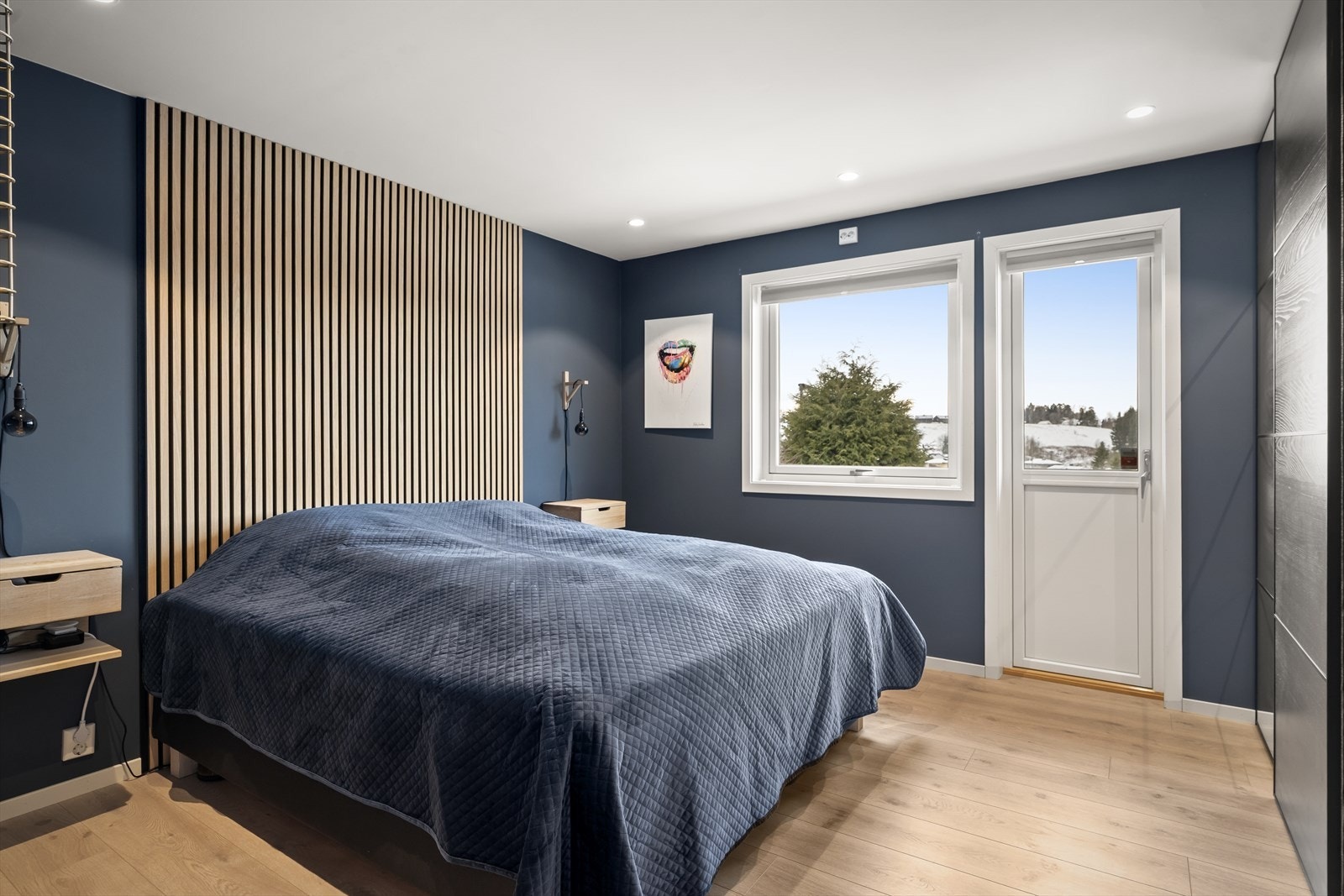 Dekorativ spilevegg som gir rommet et moderne uttrykk, kombinert med vegger malt i en behagelig blåfarge som skaper en rolig atmosfære. Galleribilde