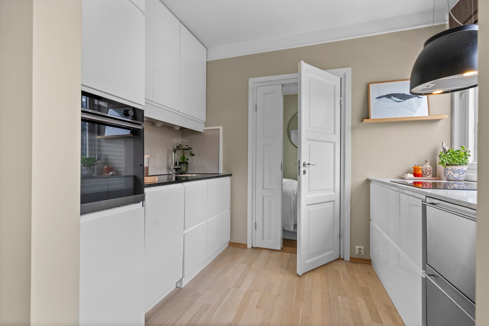 Innredning med glatte fronter og kompositt benkeplate på den ene siden og benkeplate av stein på den andre siden. Galleribilde