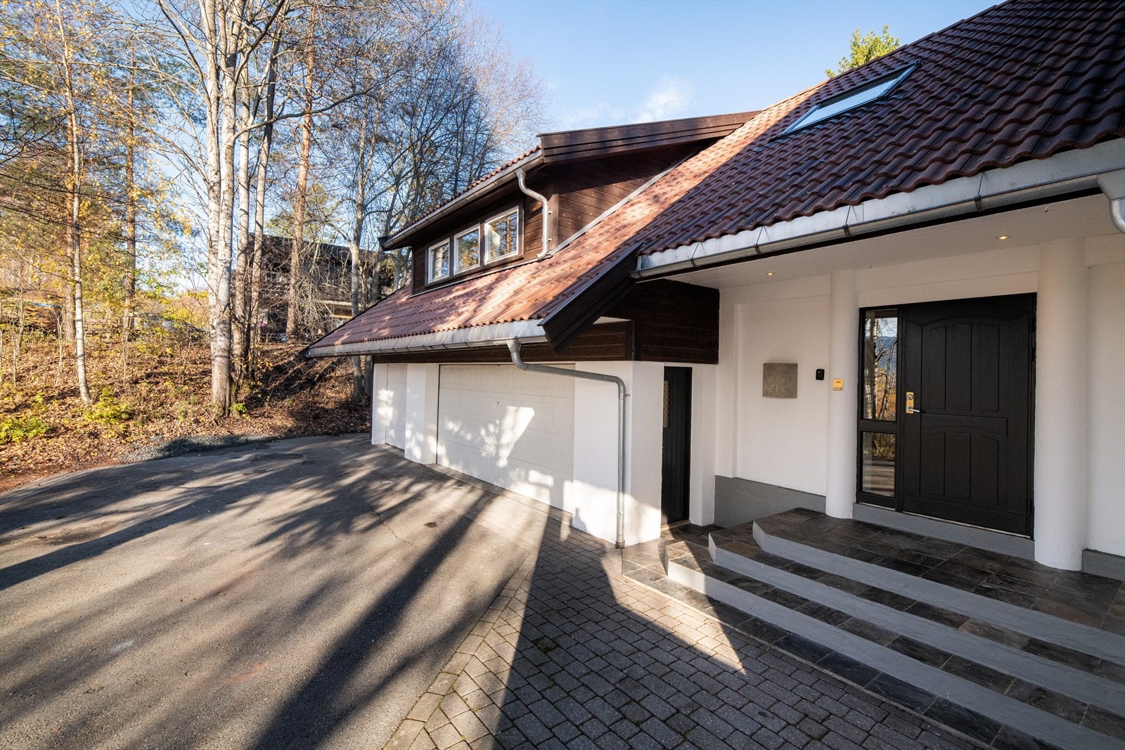 Asfaltert gårdsplass foran hovedboligen, med tilliggende trippel garasje. Galleribilde