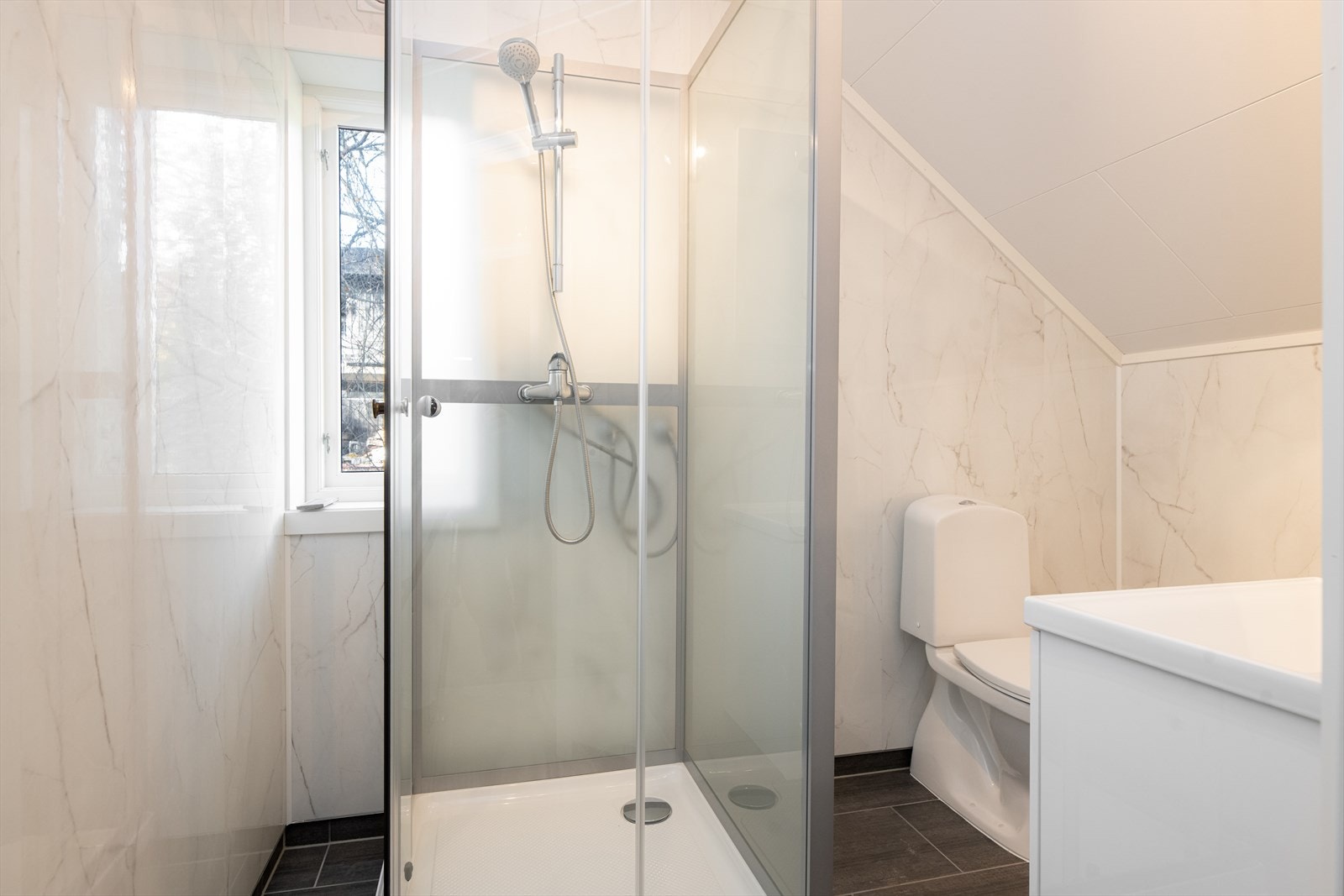 Badet har innredning i hvit utførelse med nedfelt servant, toalett og dusjkabinett. Her er også opplegg for vaskemaskin. Galleribilde