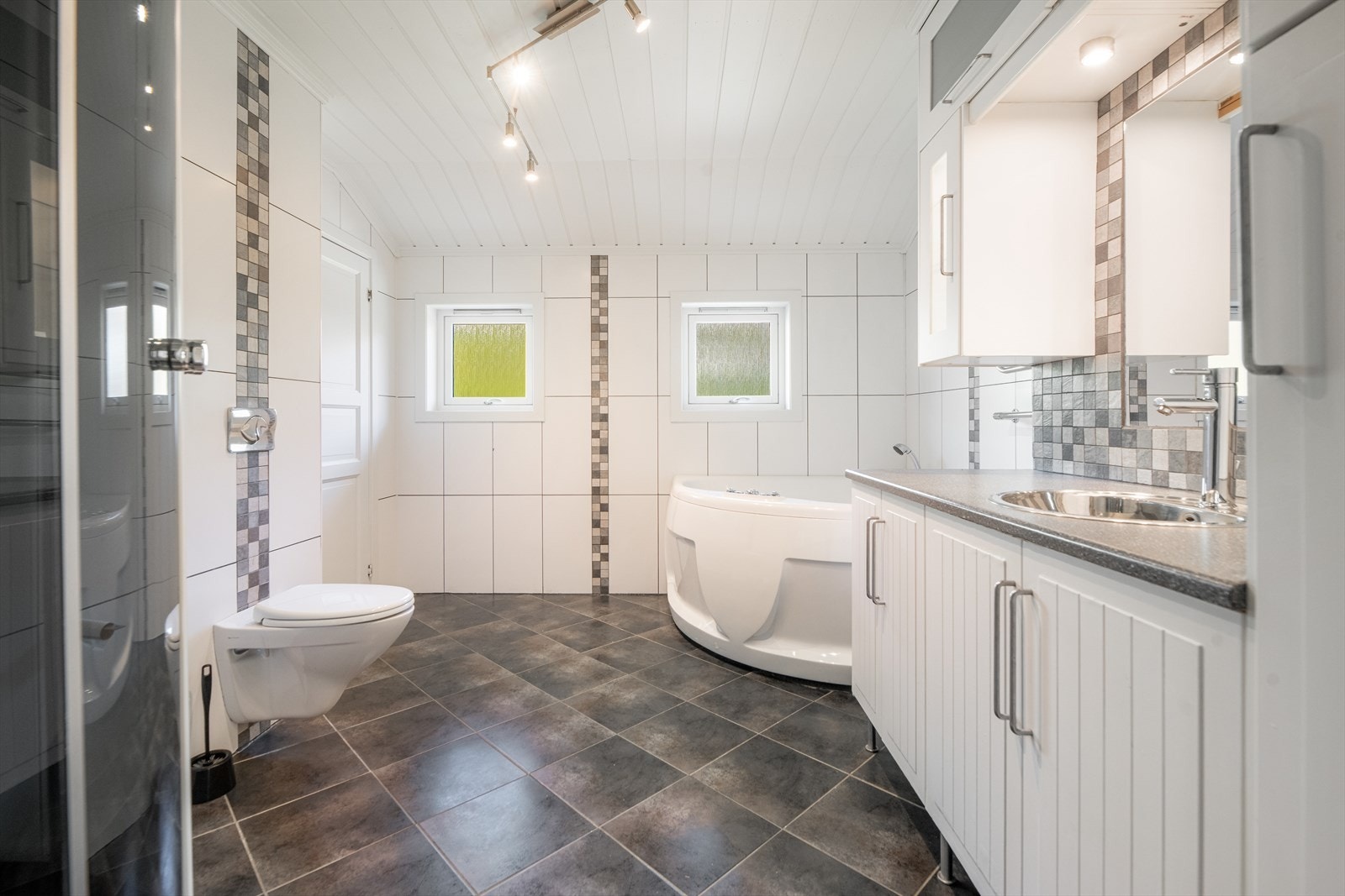 Badet i hovedboligens loftetasje er av god størrelse, med tilliggende vaskerom. Badet fra 2008 er helfliset med varmekabler i gulvet, med innslag av dekorativ mosaikkflis på veggoverflatene og rundt speilet. Galleribilde