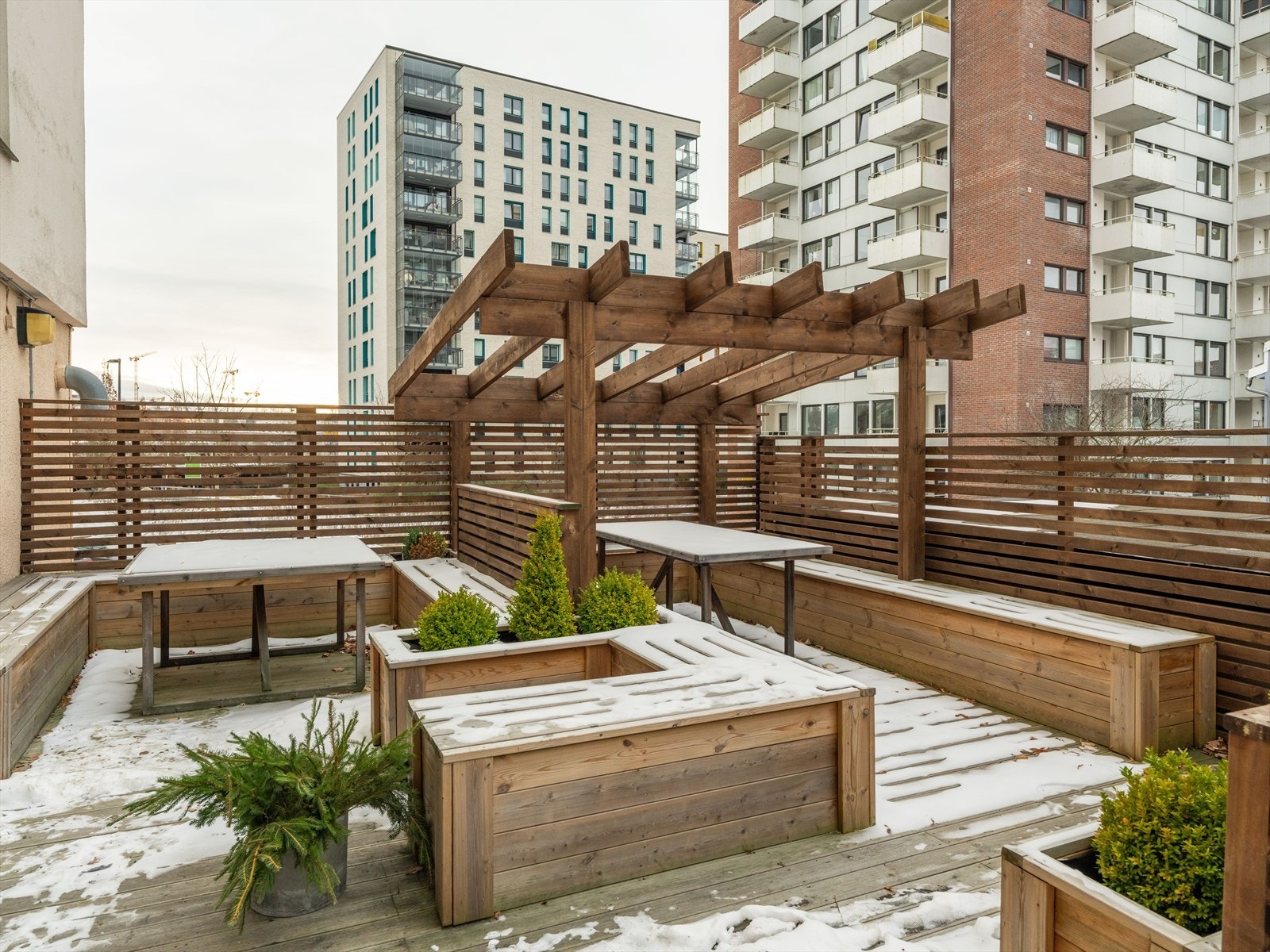 Felles uteområde med tredekke og pergola gir mulighet for utendørs opphold. Området er omgitt av beplantning og sittegrupper. Galleribilde