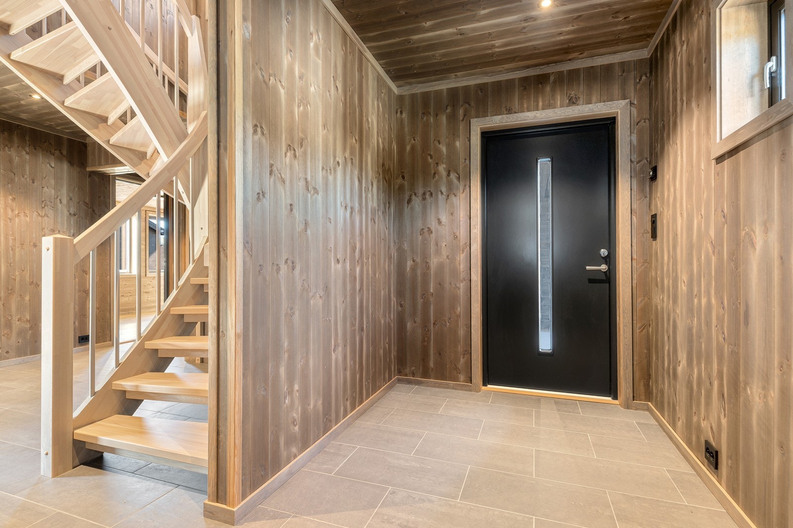 Romslig entre med flis på gulv m/varmekabler og nydelig veggpanel i mørk utførelse Galleribilde