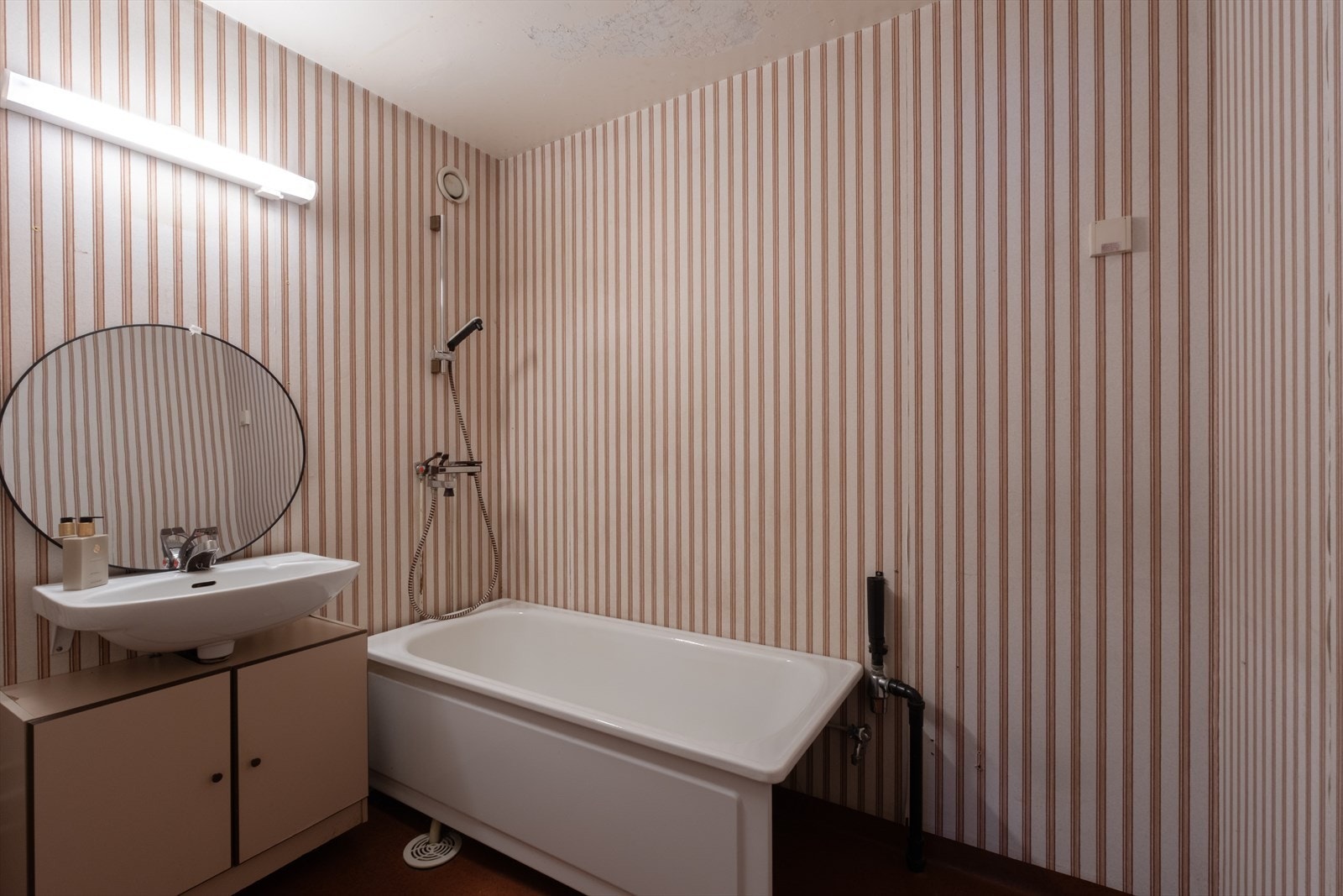 Baderom fra byggeår med våtromstapet på vegger, belegg på gulv og malt betong i tak. Galleribilde