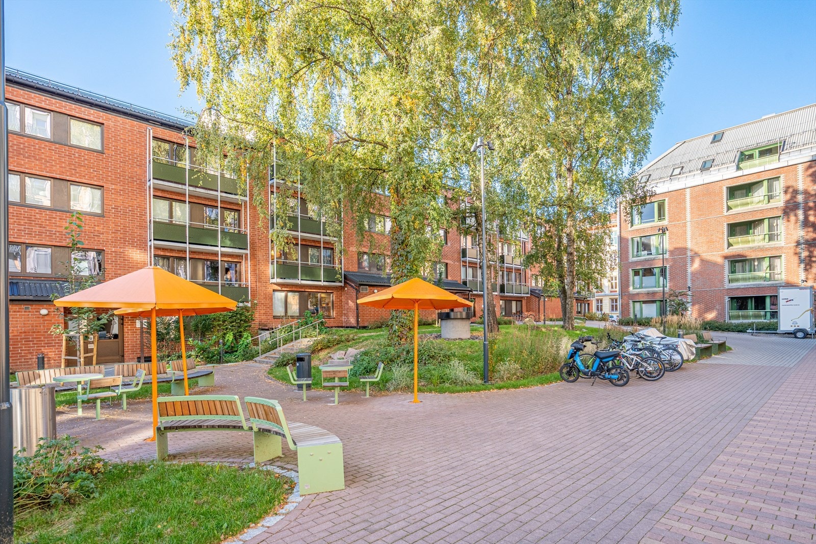 Tomten er pent opparbeidet med brostein, plen og beplantning. Videre tilbyr den sittegrupper og sykkelparkering. Galleribilde