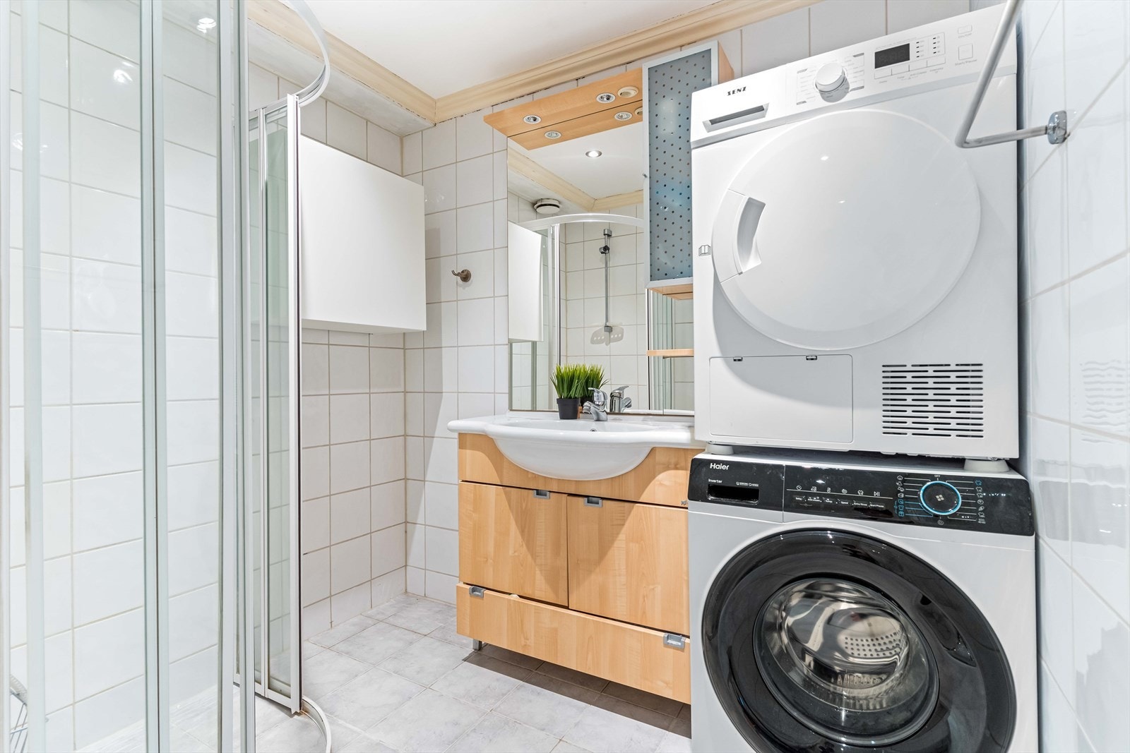 Innredningen består av servant- og underskap, dusjhjørne med glassdører, gulvstående wc, v.v.bereder, samt opplegg for vaskemaskin og tørketrommel. Galleribilde