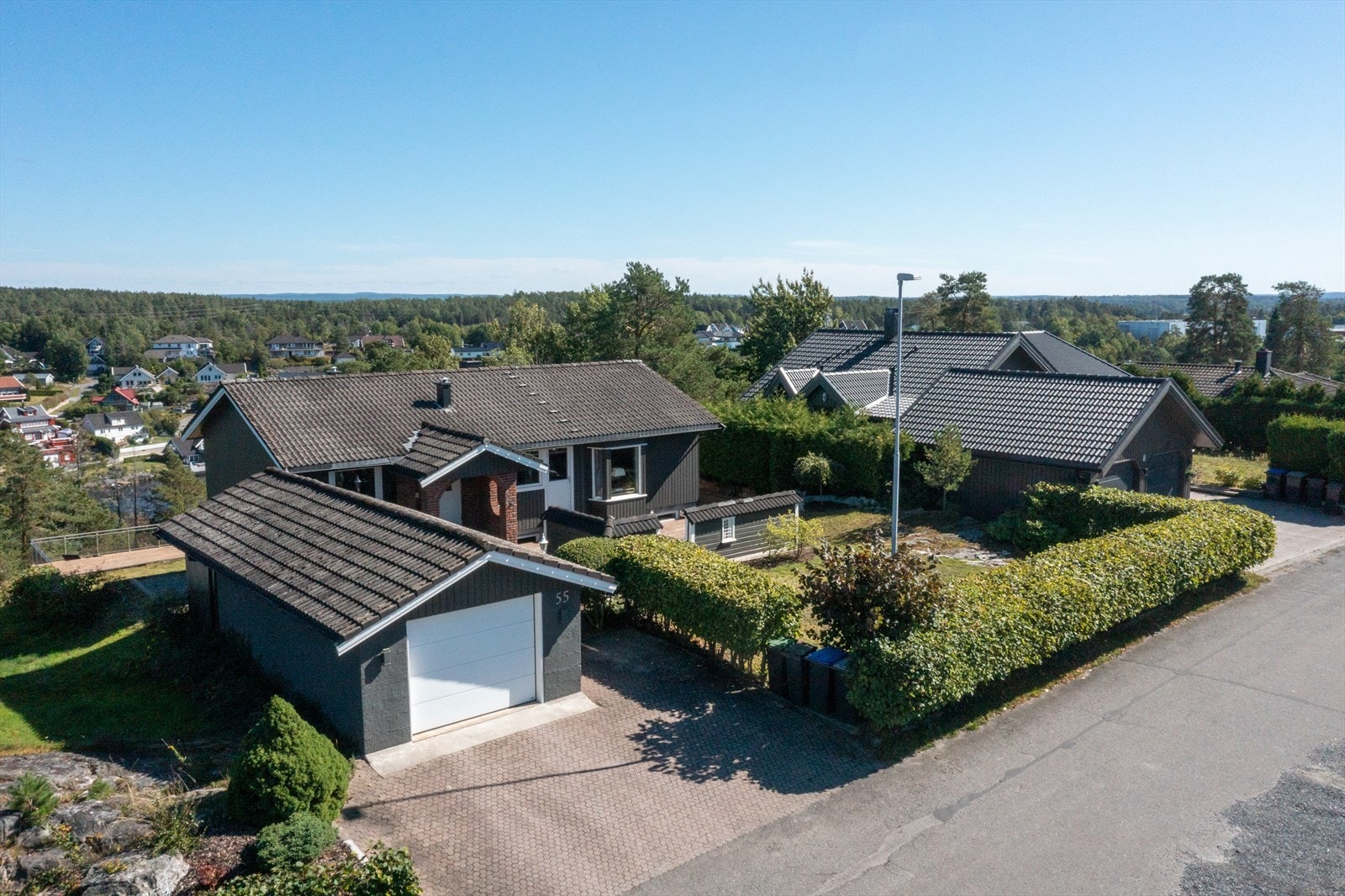 Eiendommen ligger rolig til i blindvei, med lite trafikk og svært barnevennlige omgivelser. Tomten er pent opparbeidet og innrammet med hekk og beplantning, som skaper et skjermet og privat uteområde. Foto: Studio Eik Galleribilde