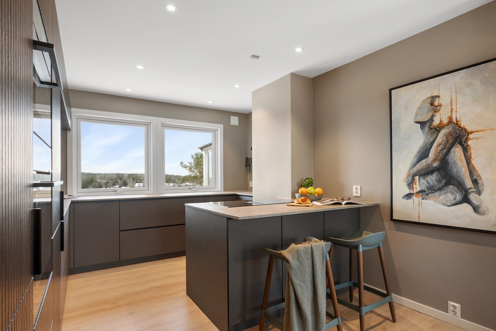 Kvik kjøkkenet fra 2024 fremstår moderne og stilrent, plassert i en egen nisje og naturlig avgrenset mot spisestuen av en kjøkkenøy Galleribilde